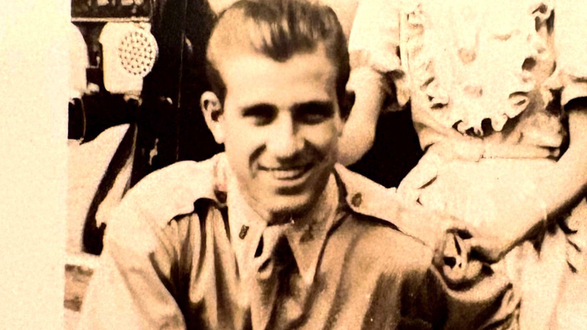 An old sepia photograph of a young Lt. Barton. He is wearing a light coloured army uniform shirt and tie. He is smiling broadly at the camera.