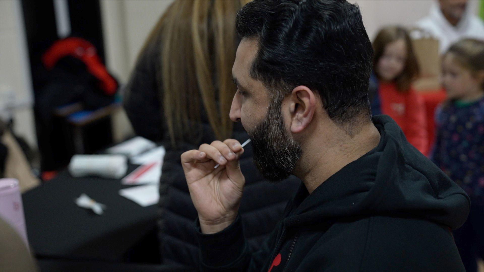 A man swabs the back of his throat