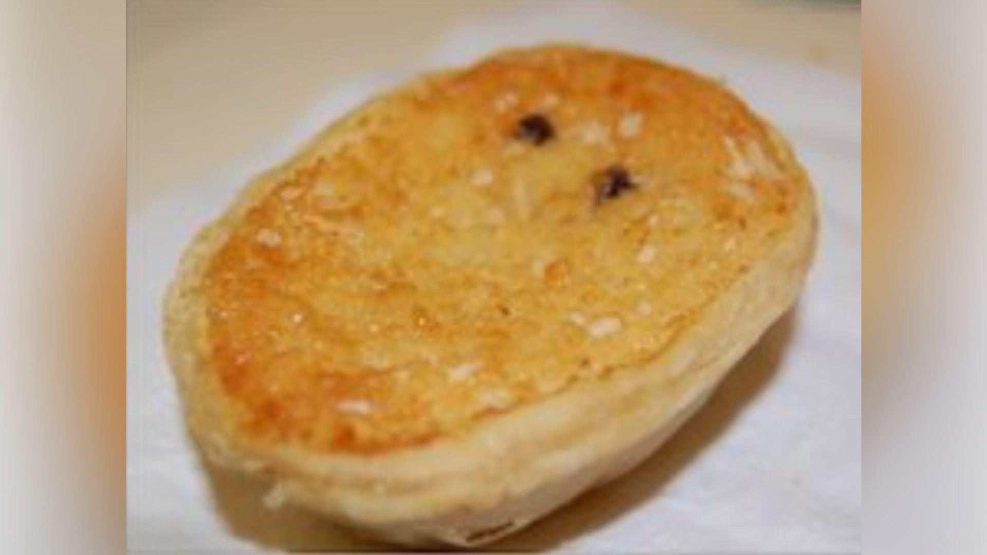 Oval-shaped cheesecake with golden brown top and puff pastry around the outside. Two currants are visible on the surface.