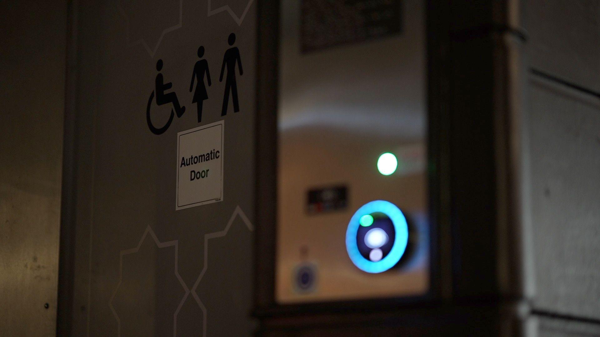 A close up shot of a public loo with the wording 'automatic door' with signs showing it is a female, male and accessible loo. 