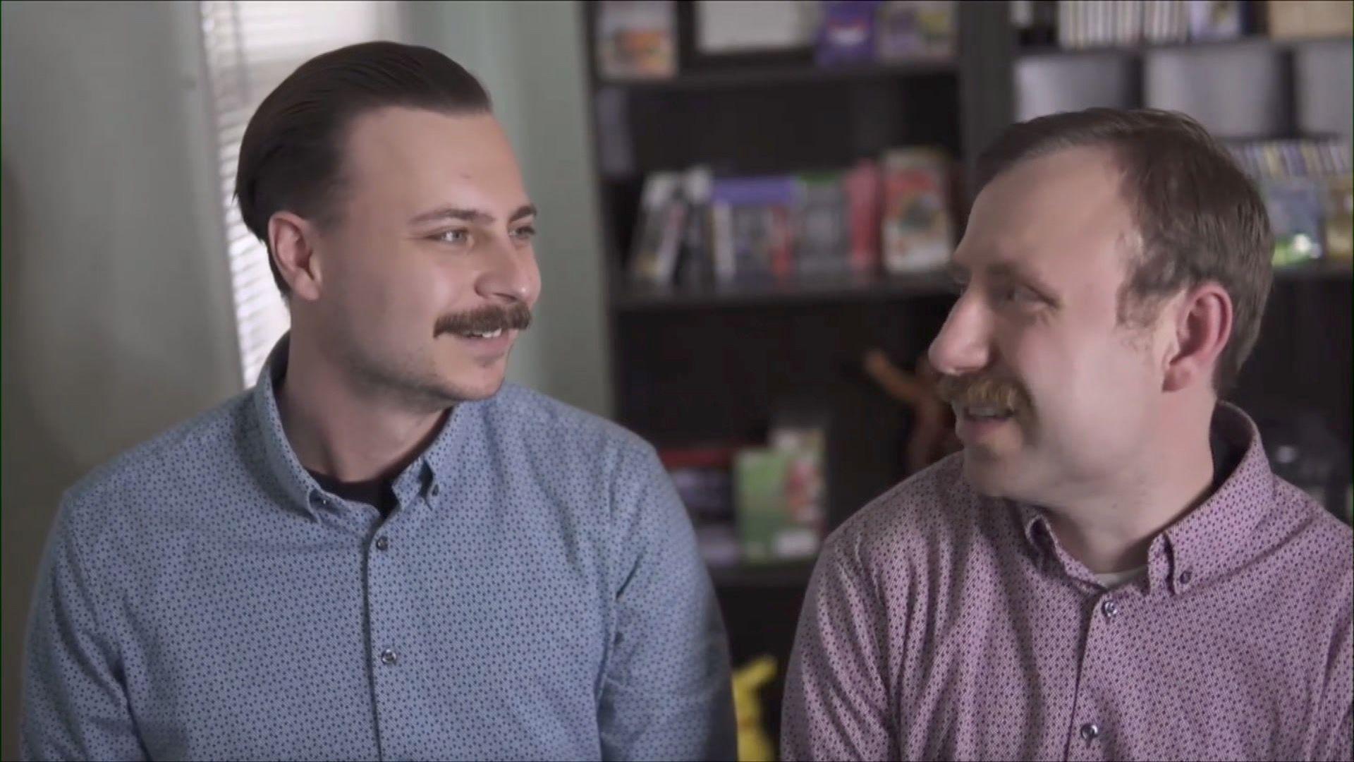 Two men with moustaches look at each other