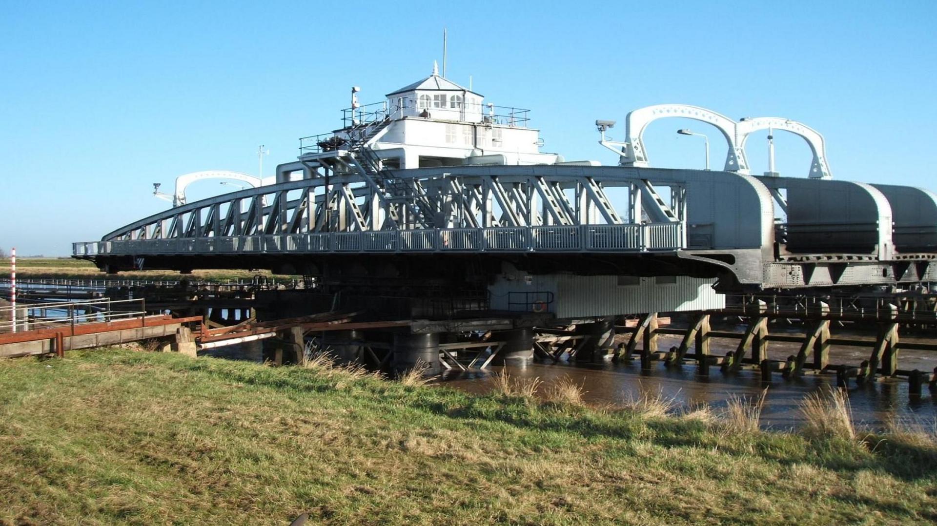 The steel structure of the bridge has been swung at a right angle to the road to allow boats to continue up the River Nene.