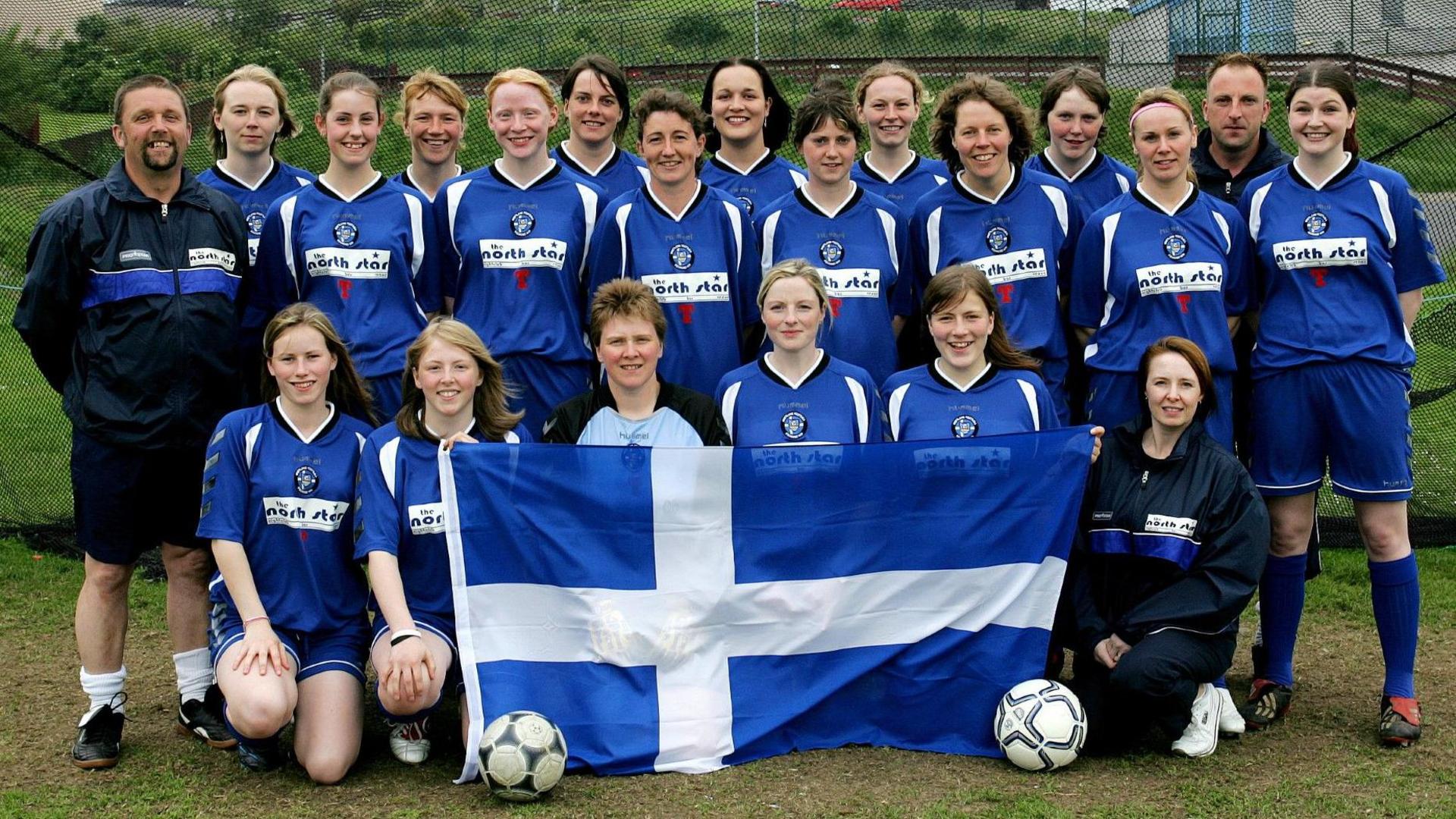 A group shot of the squad wearing a blue and white kit and displaying Shetland's flag.