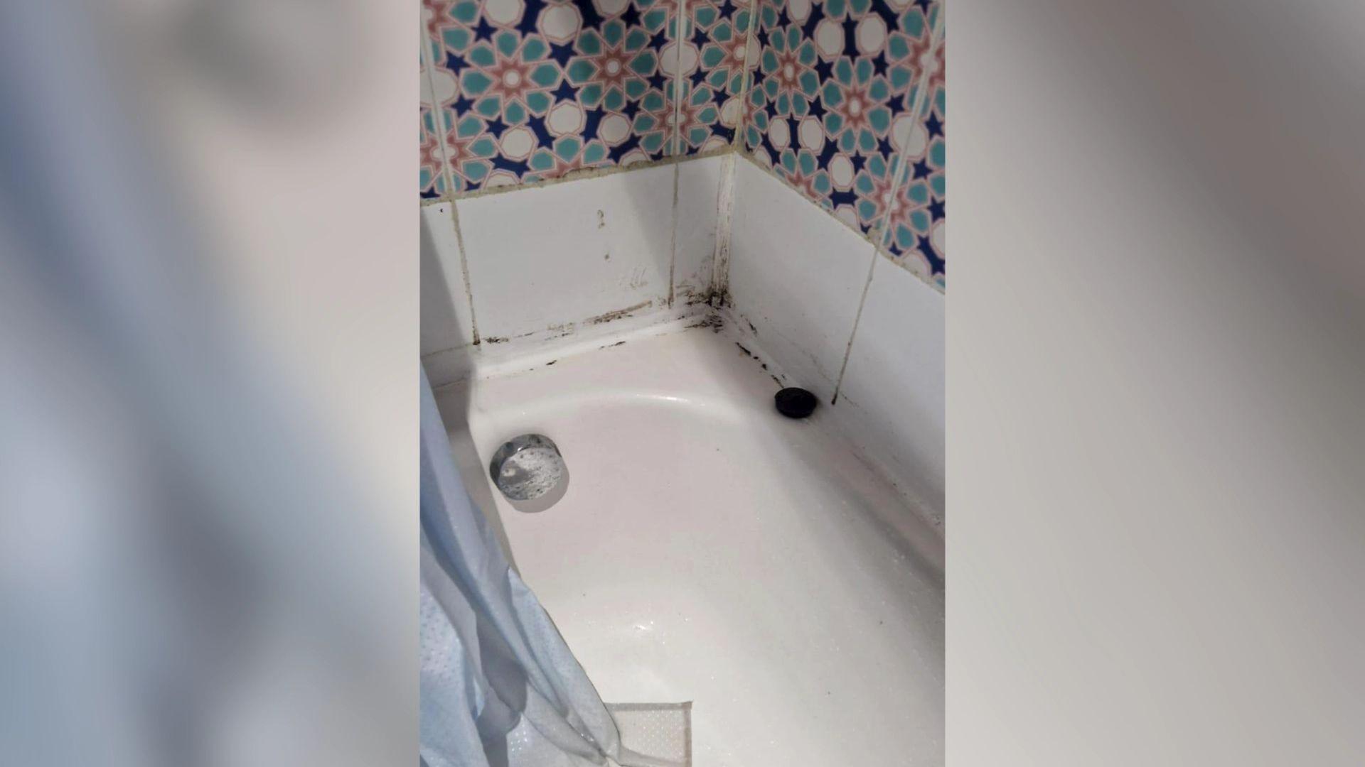 A bath with dark marks in the corner. 