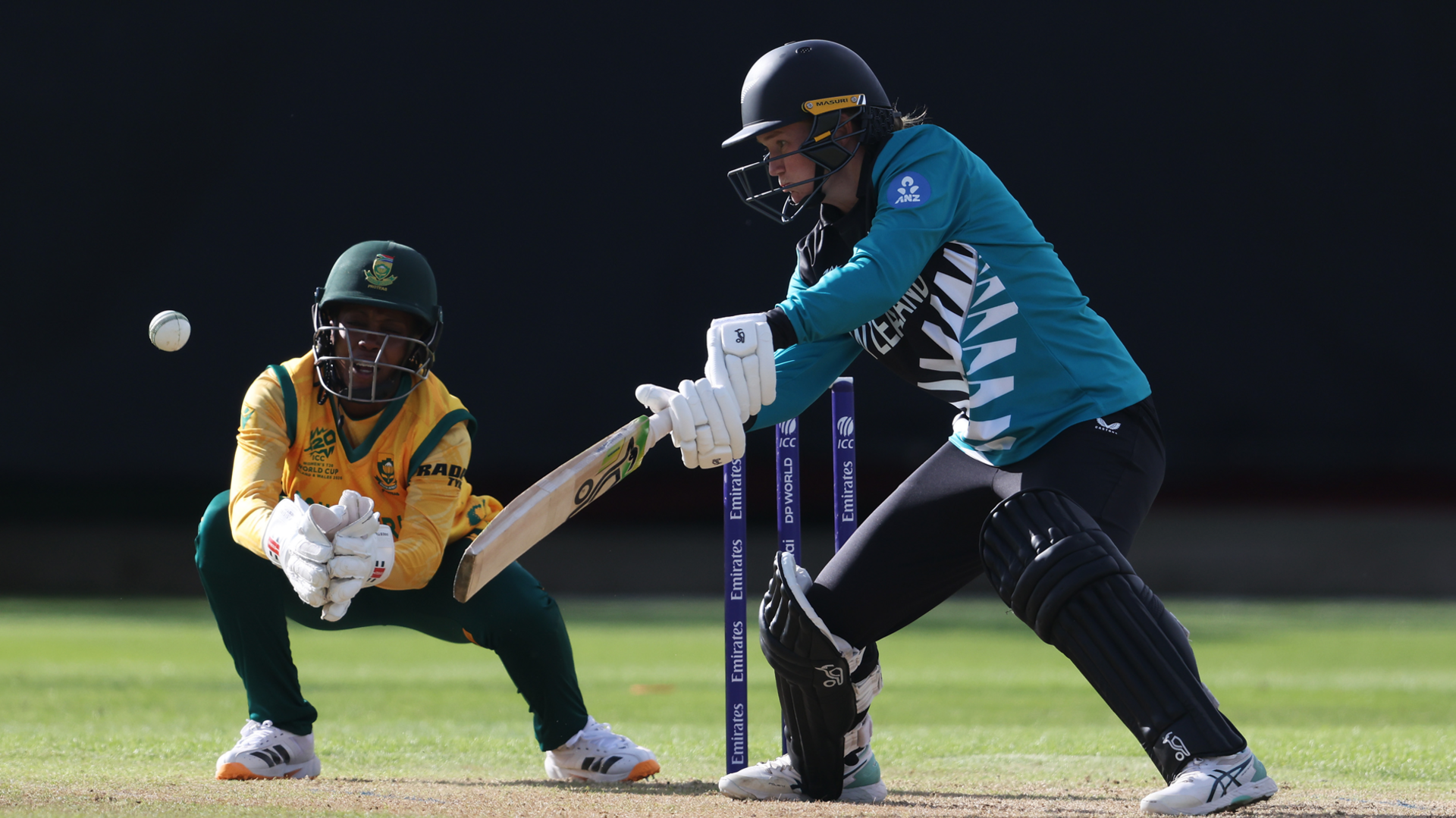 Maddy Green of New Zealand hits the ball towards the boundary, as Karabo Meso of South Africa watches on