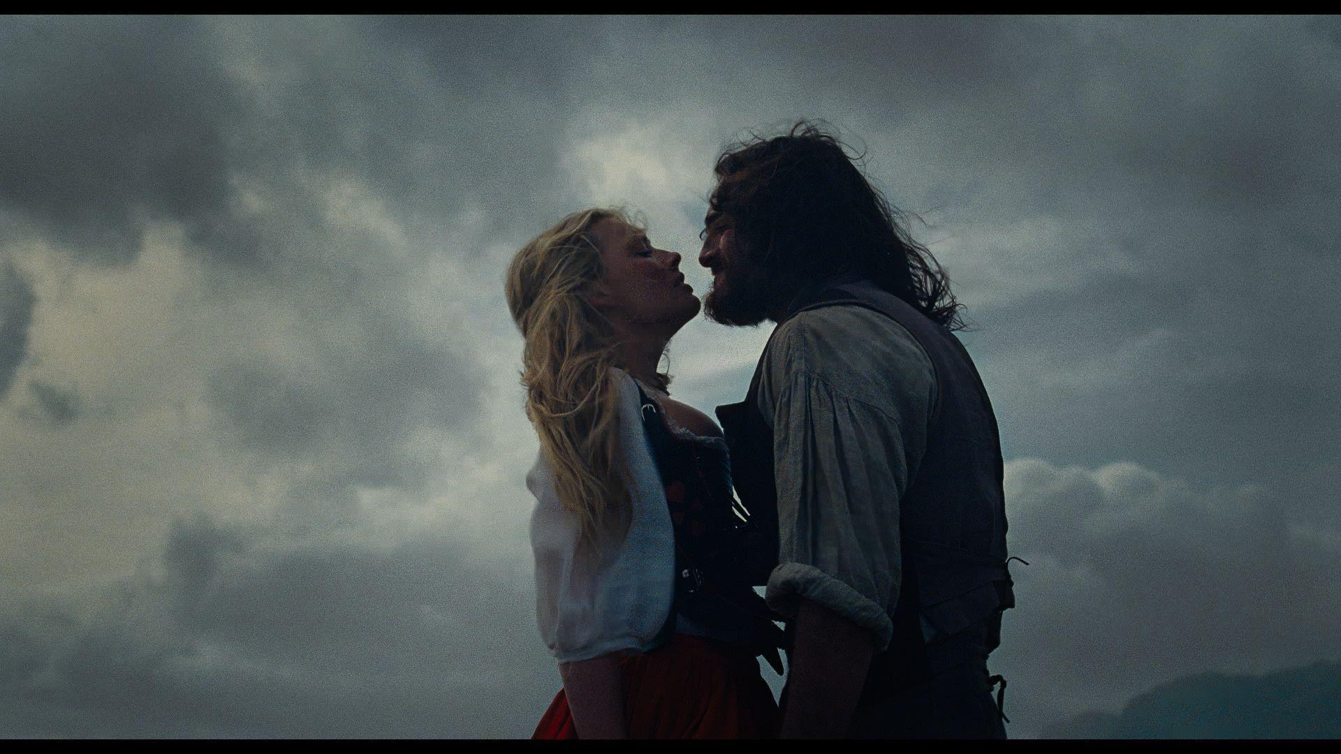 Margot Robbie and Jacob Elordi look at each other dressed in period clothing for the new Wuthering Heights film. The weather behind them is moody and cloudy.