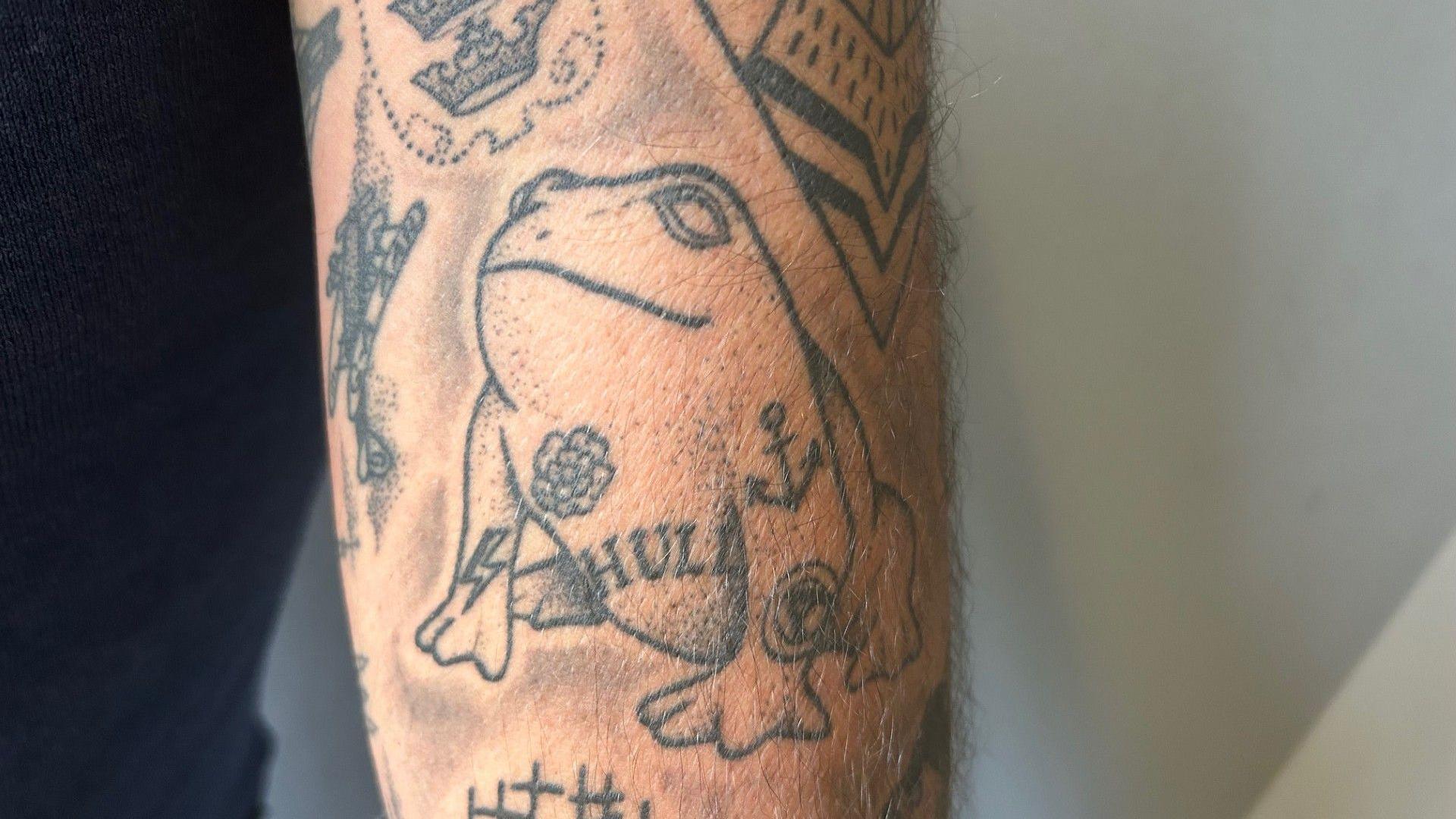 A tattoo of a toad, among others on an arm.