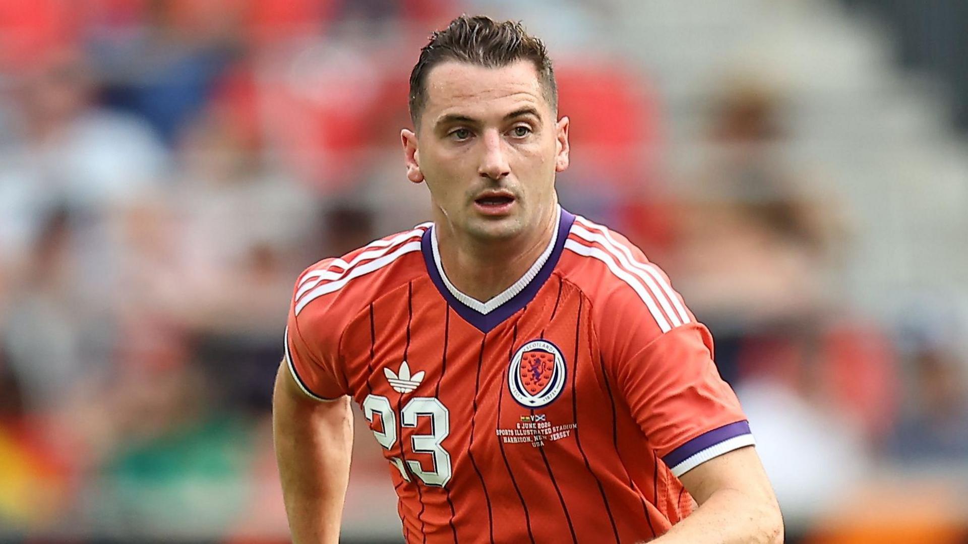 Kenny McLean, wearing Scotland's red away shirt with white and blue trim, in action against Bolivia on 6 June