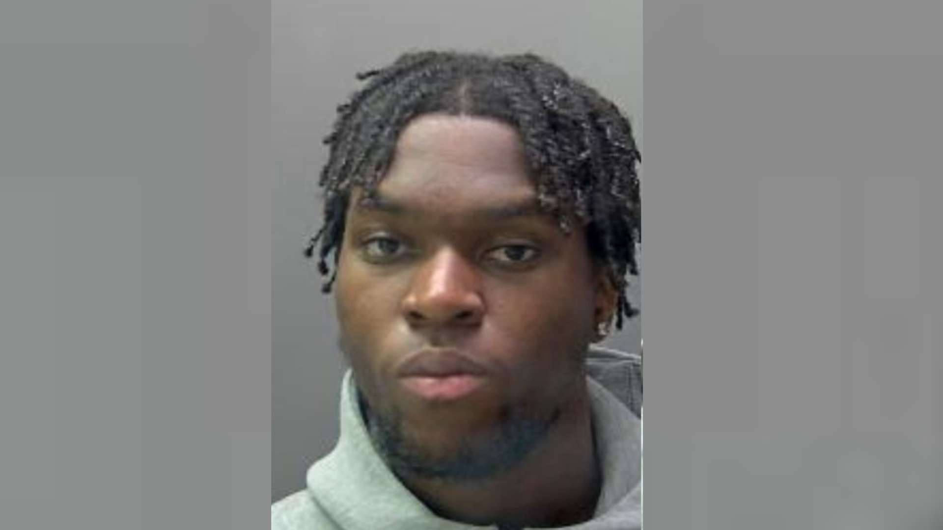Image shows police mugshot of Desmond Bonato, who has short braided hair and is wearing a grey hoodie