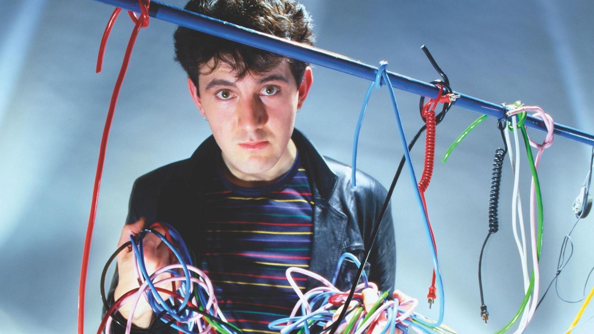 Dave Ball holds up an array of multi-coloured patch cables from an early analogue synthesizer