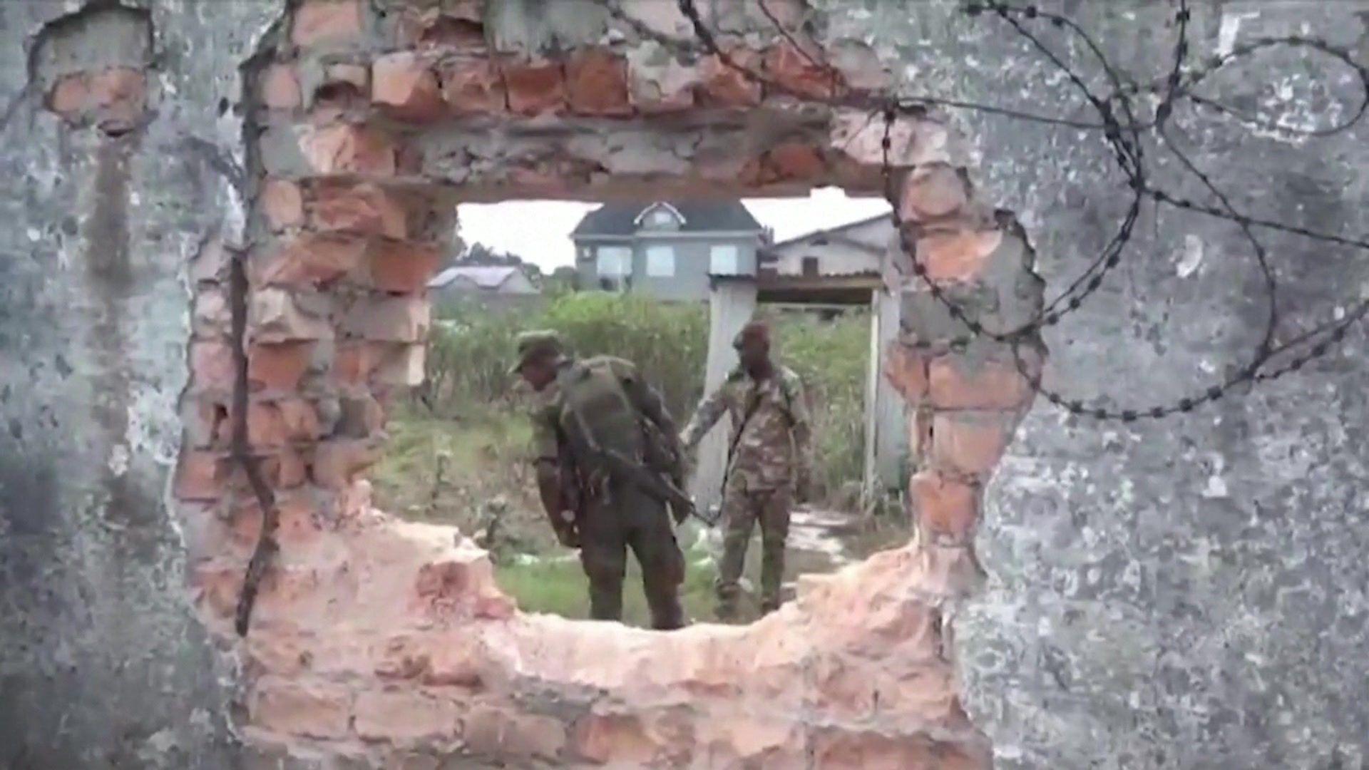 Soldiers seen through a whole in a brick wall