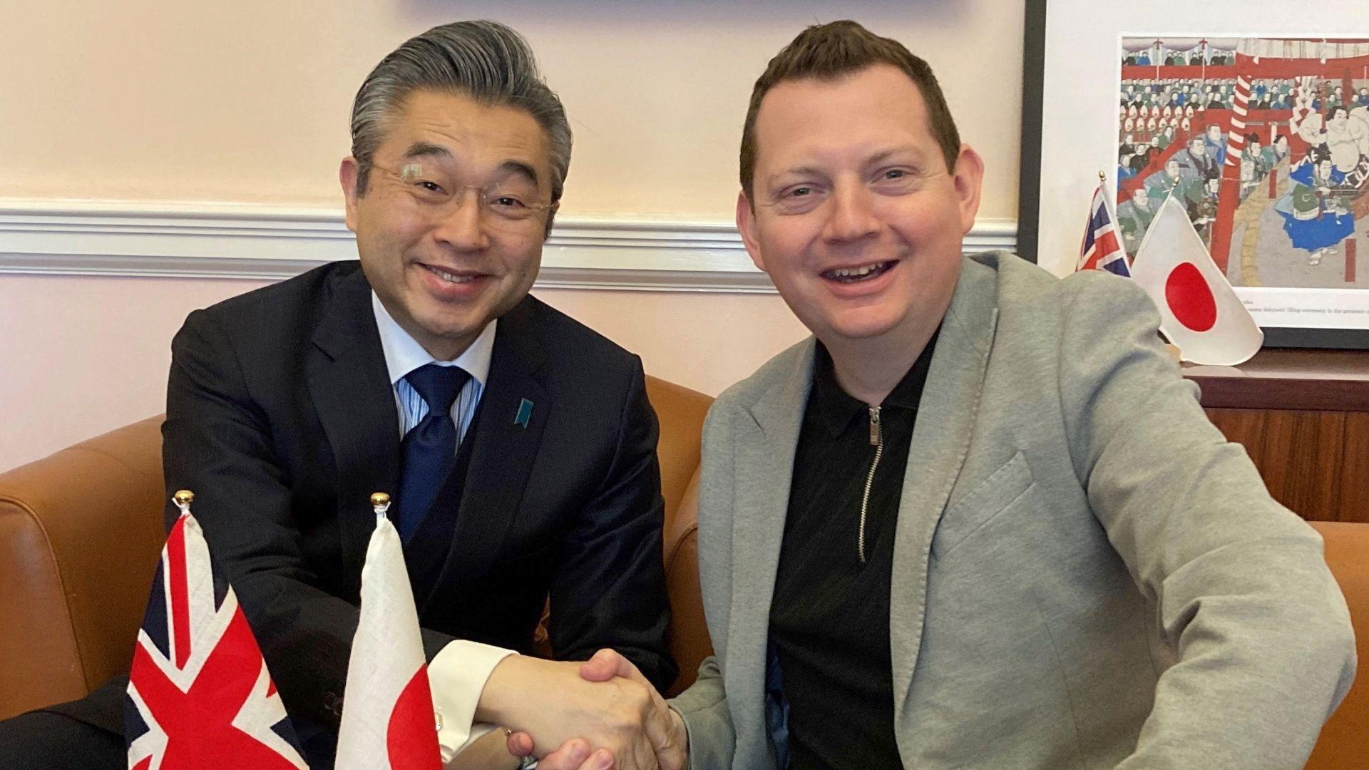 Japanese ambassador Hiroshi Suzuki and 5 live's Matt Chorley smile and shake hands