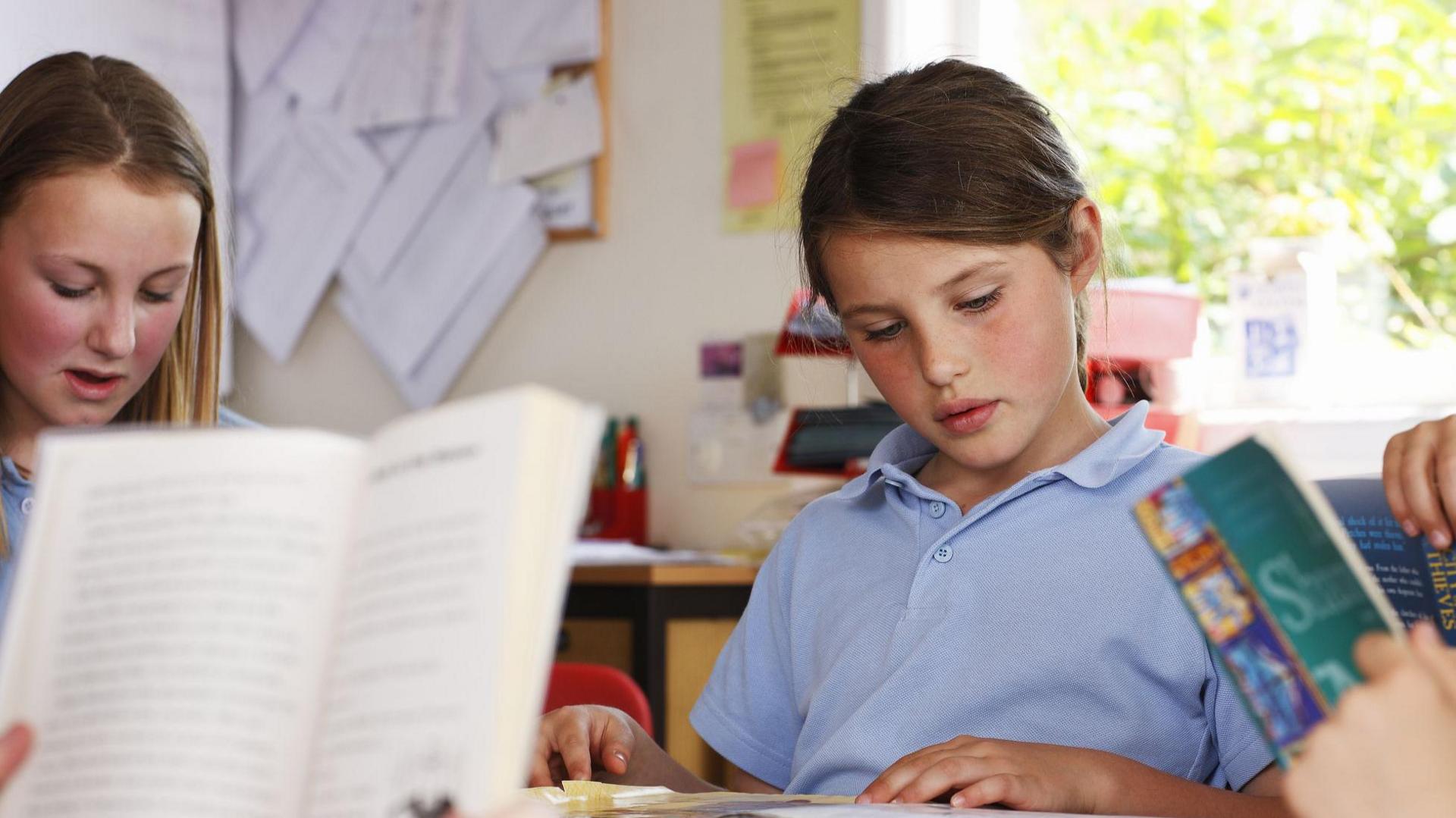 A girl reading in a classroom. 