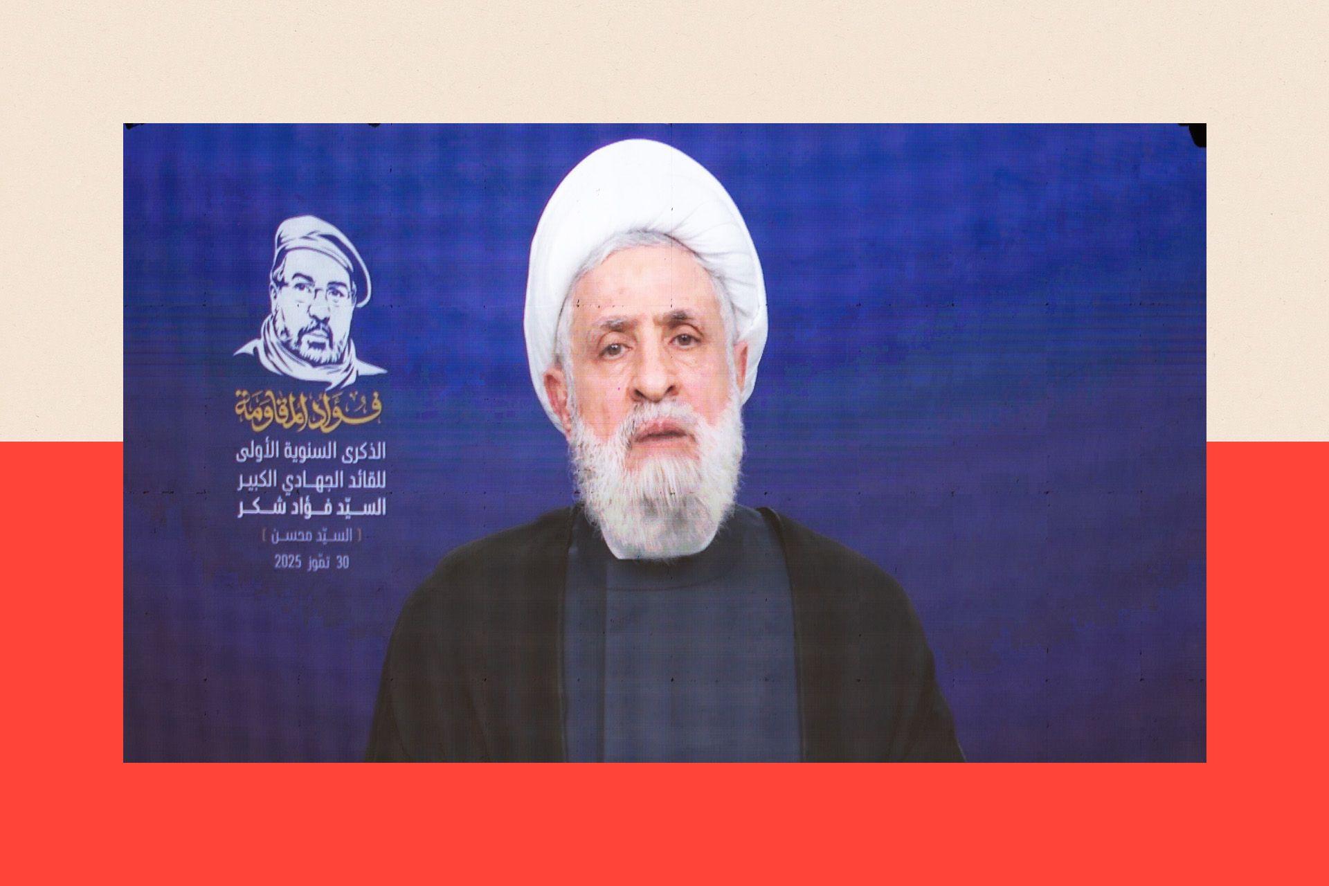Naim Qassem speaks on a screen. He wears black clothes and a white turban.