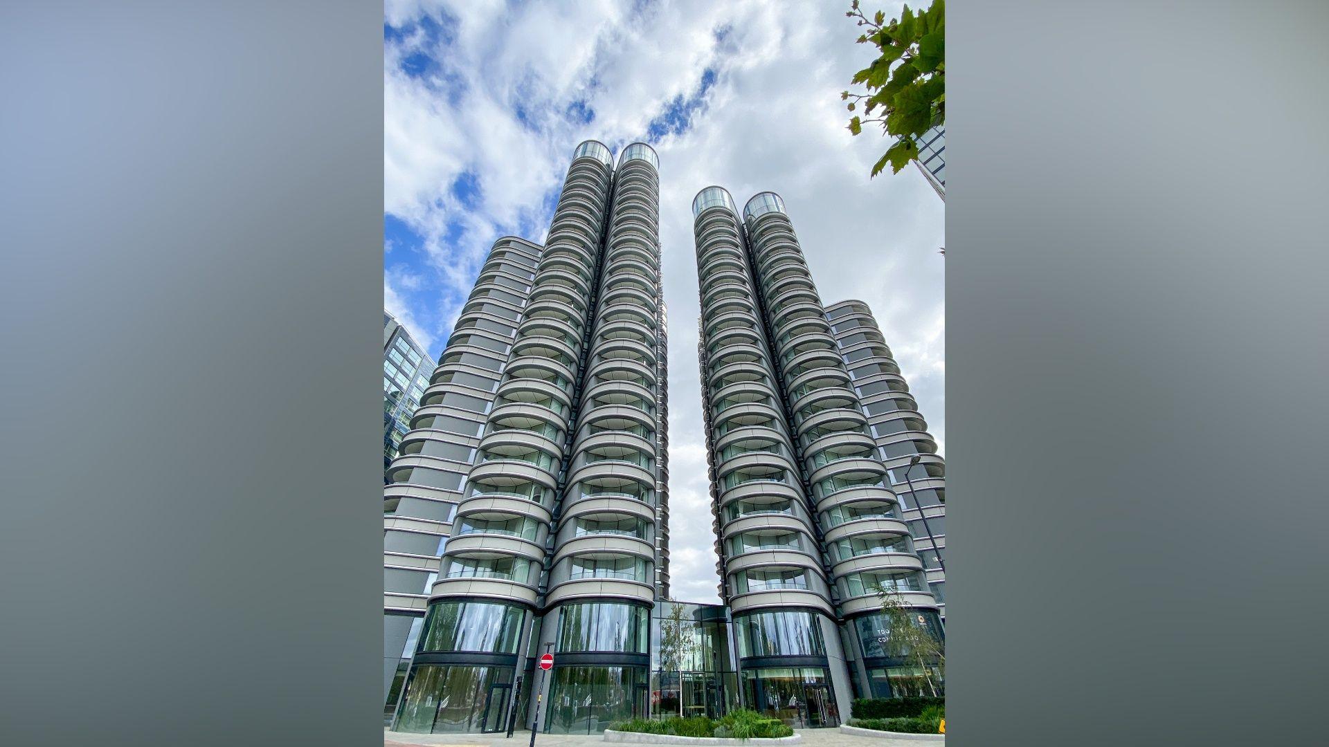 A modern apartment building consisting of four tall towers with balconies in a grey building material. 