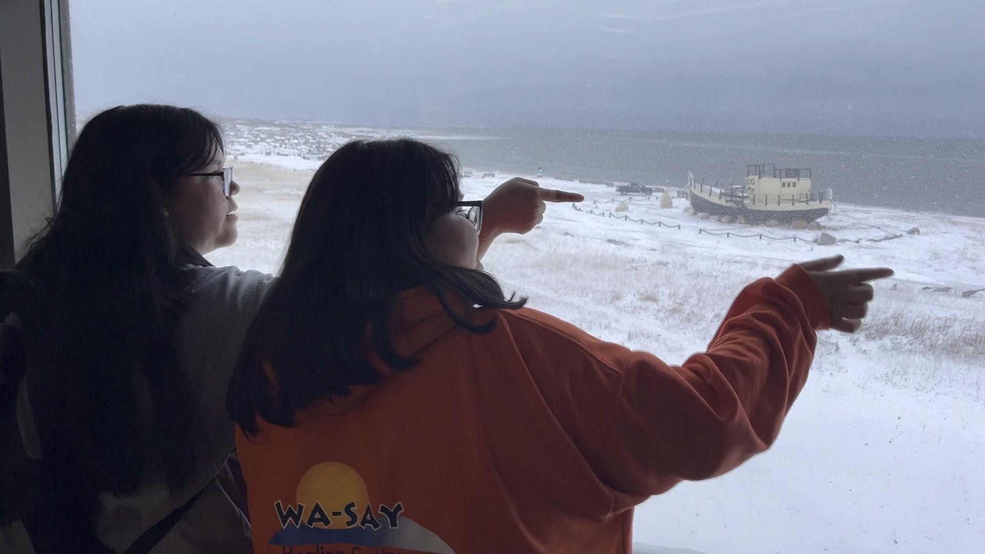 Children at Churchill School look out over the Hudson Bay and spot a polar bear being moved