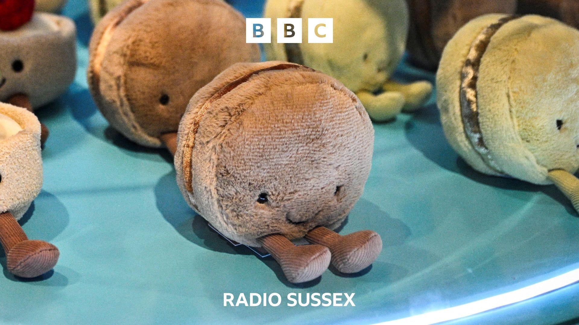 A selection of jellycat macaron stuffed toys sit on an aqua blue display shelf.