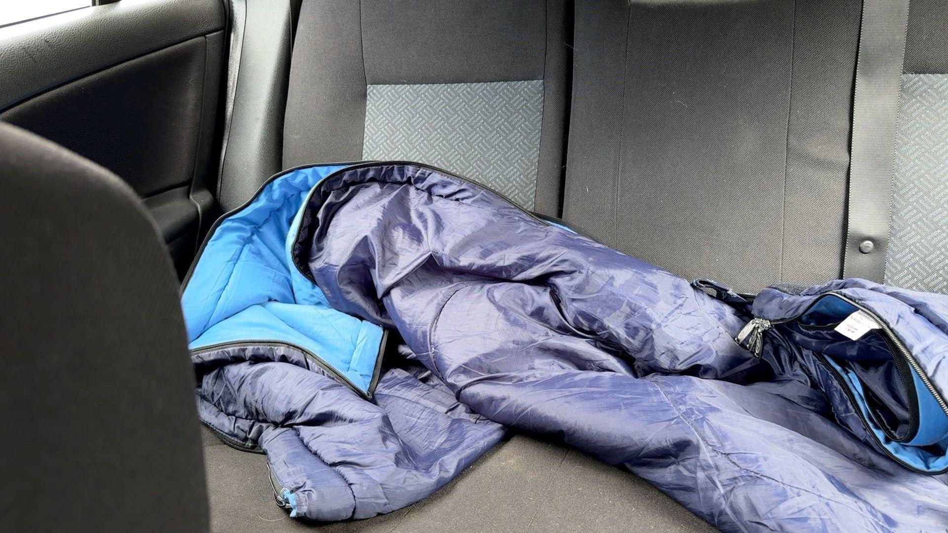 A purple and blue coat lies in the backseat of a car.