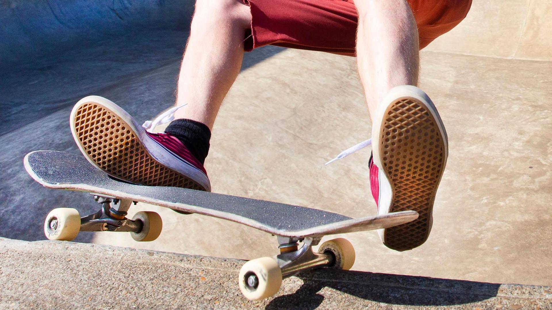 A person wearing red shorts and shoes on a skateboard. The skater is visible from knees down.