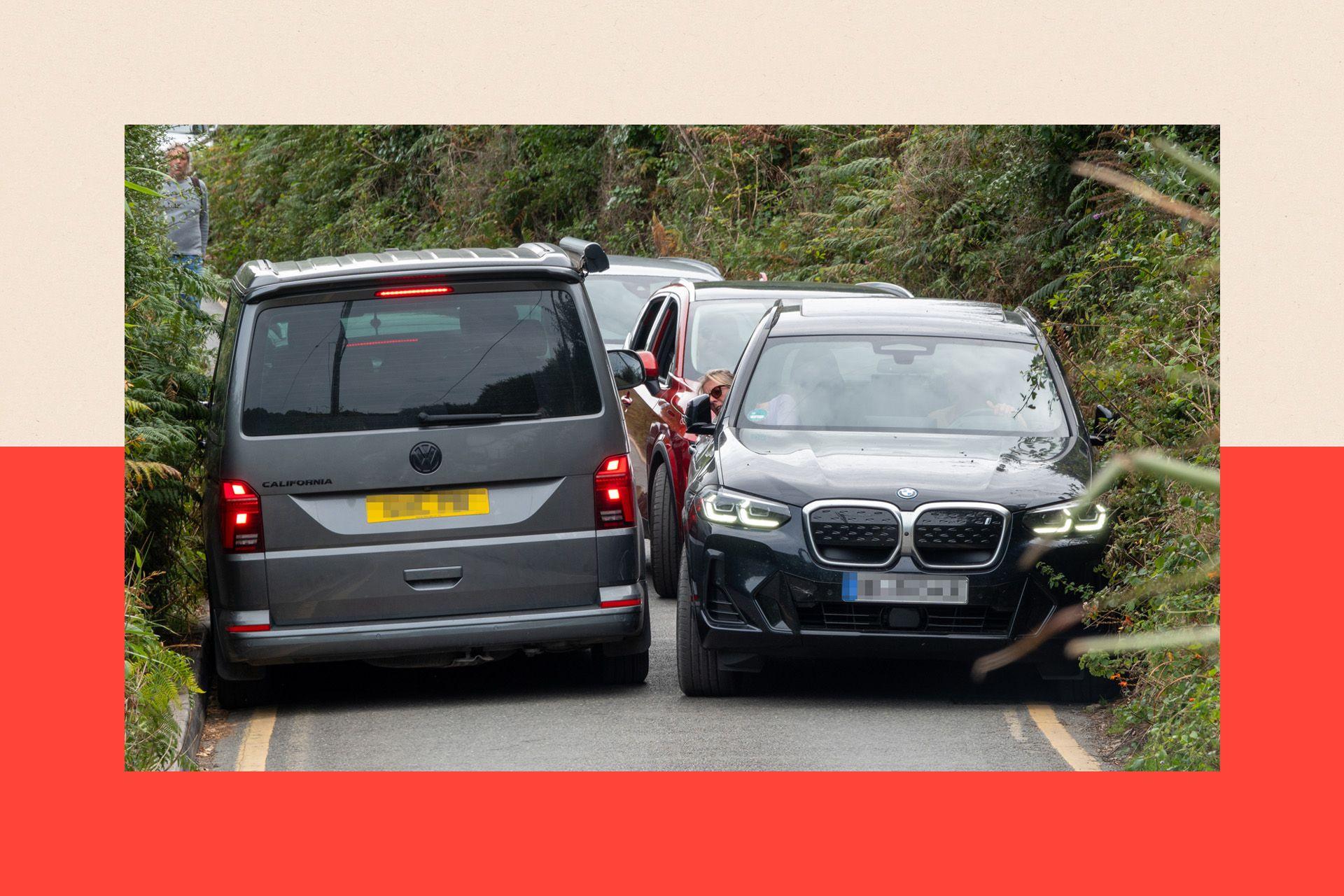 Vehicles try to squeeze past each other in the narrow road and lanes at Porthcurno in Cornwall, England
