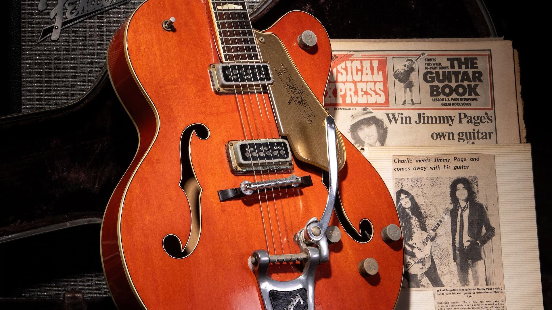 A 1957 Gretsch guitar in a reddish coloured wood. Next to it, old magazine and newspaper clipping showing where it came from