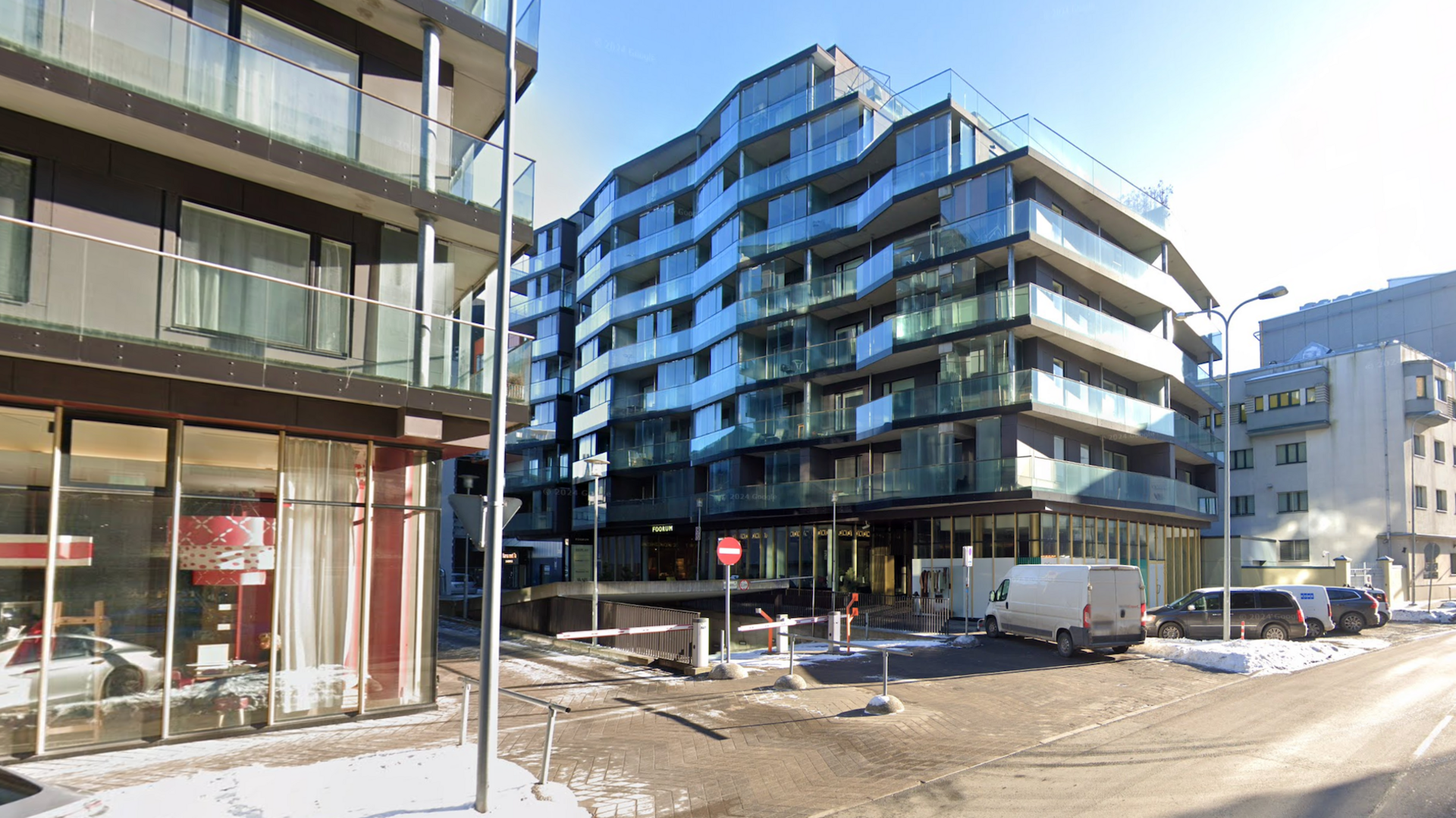 A medium size glass building on a street in Tallinn with snow on the ground.