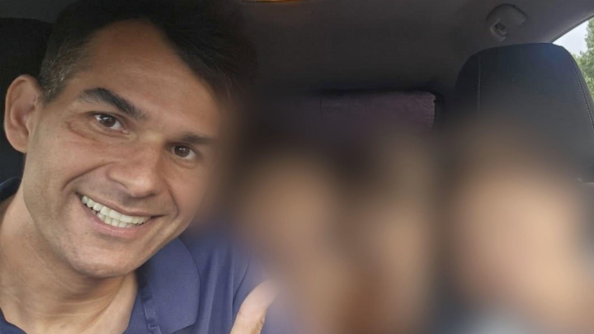 A man in a blue top smiling at the camera. The background has been blurred out.