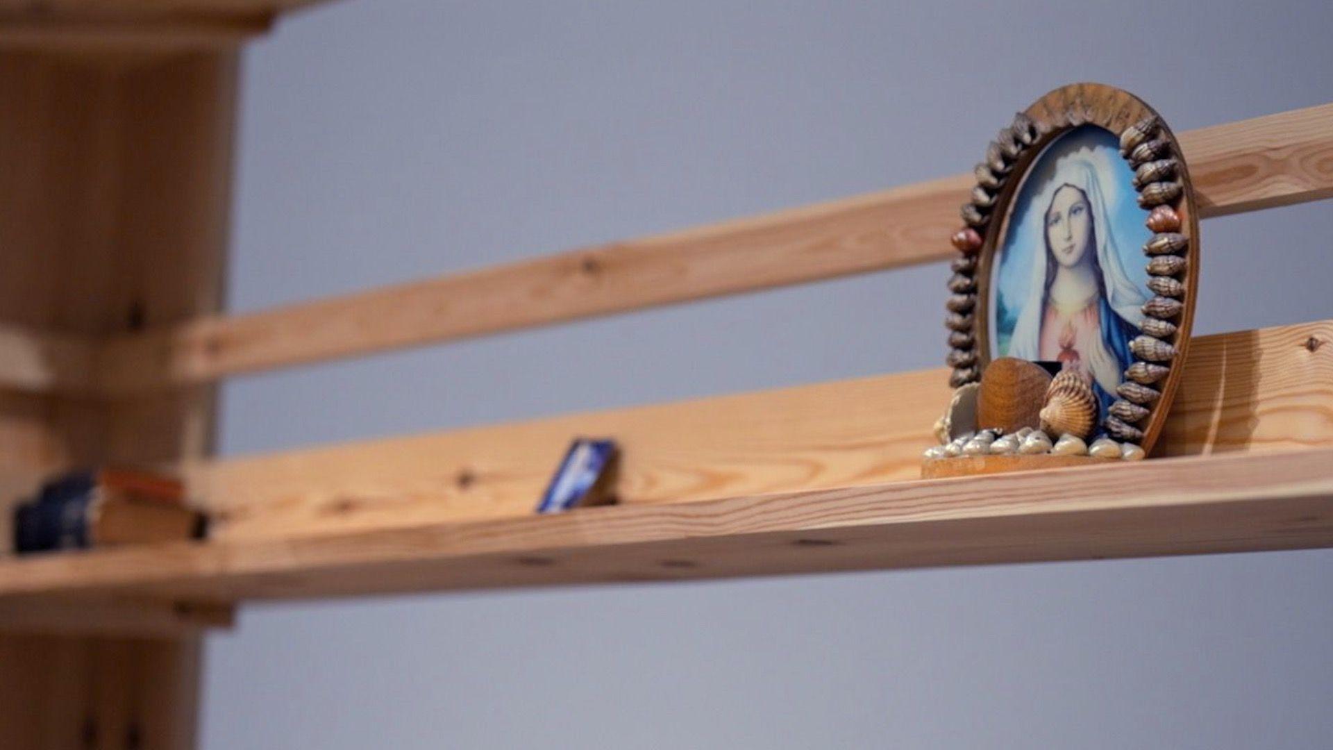 A wooden structure with various objects on the shelves, including a framed picture of the Virgin Mary.