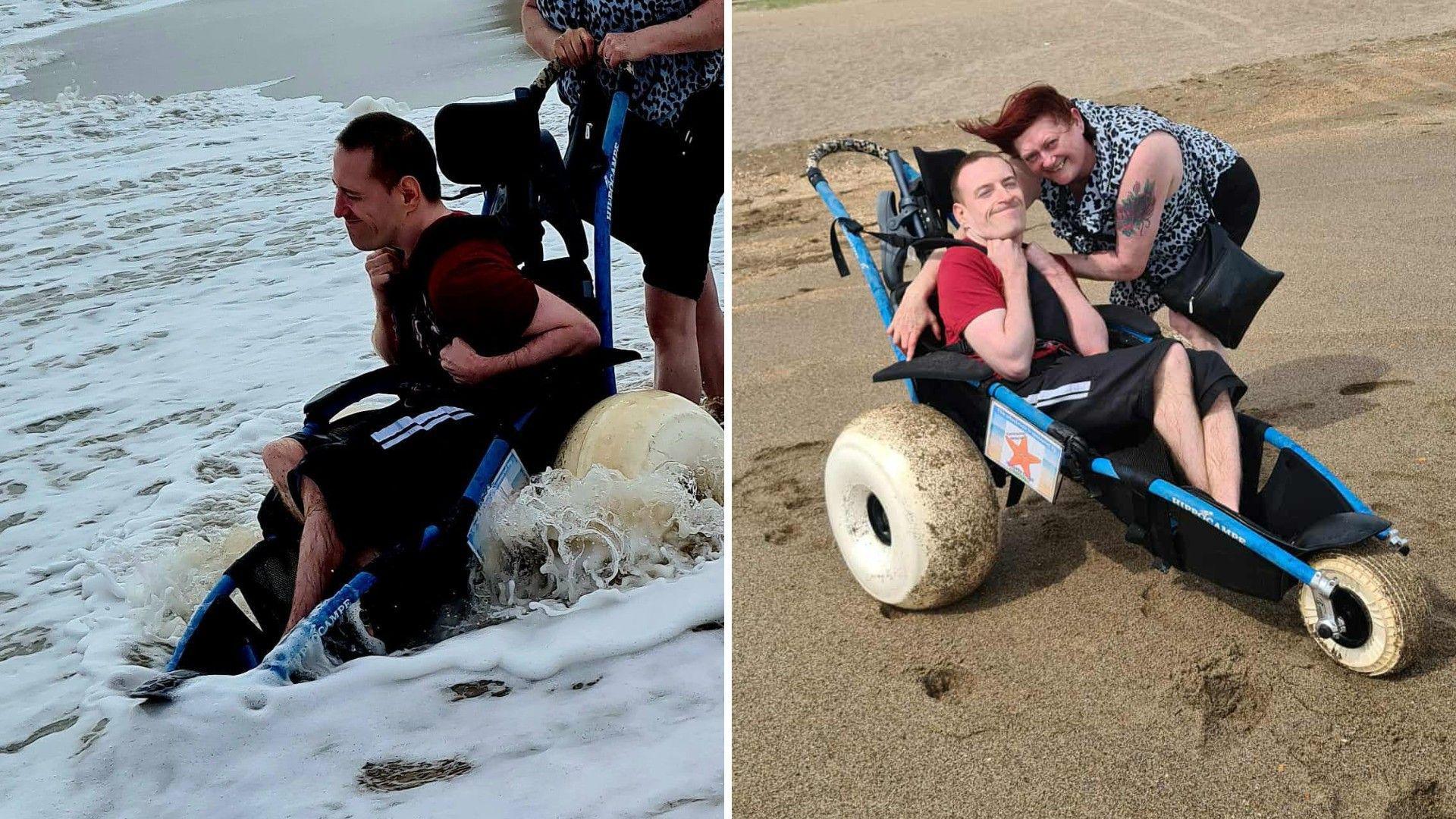 Two photos side-by-side of a man wearing a red top and black shorts in a beach wheelchair, which is extended at the front. He is holding his arms up and is smiling. In one of the pictures, he is in the sea in shallow water, with a second person holding on to the wheelchair. In the second picture, he is on a sandy beach accompanied by a woman with windswept hair, wearing a black-and-white top. She is leaning with her arm around him and smiling.