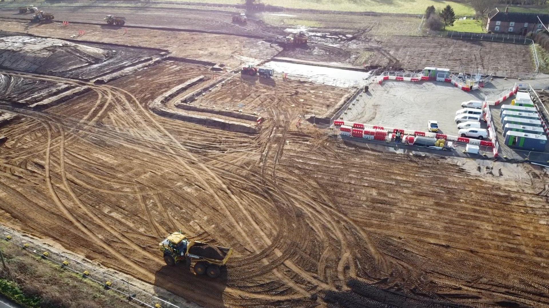 Drone shot showing construction compound with vehicles and earthmoving equipment