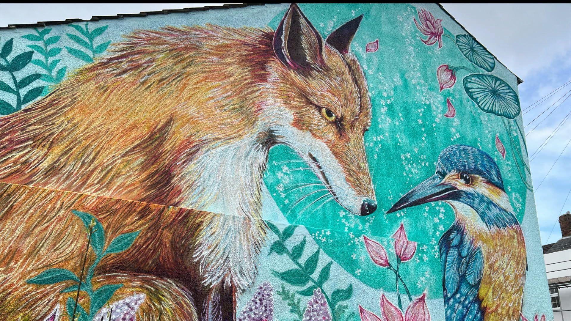 Mural on the side of a building of a fox and a bird