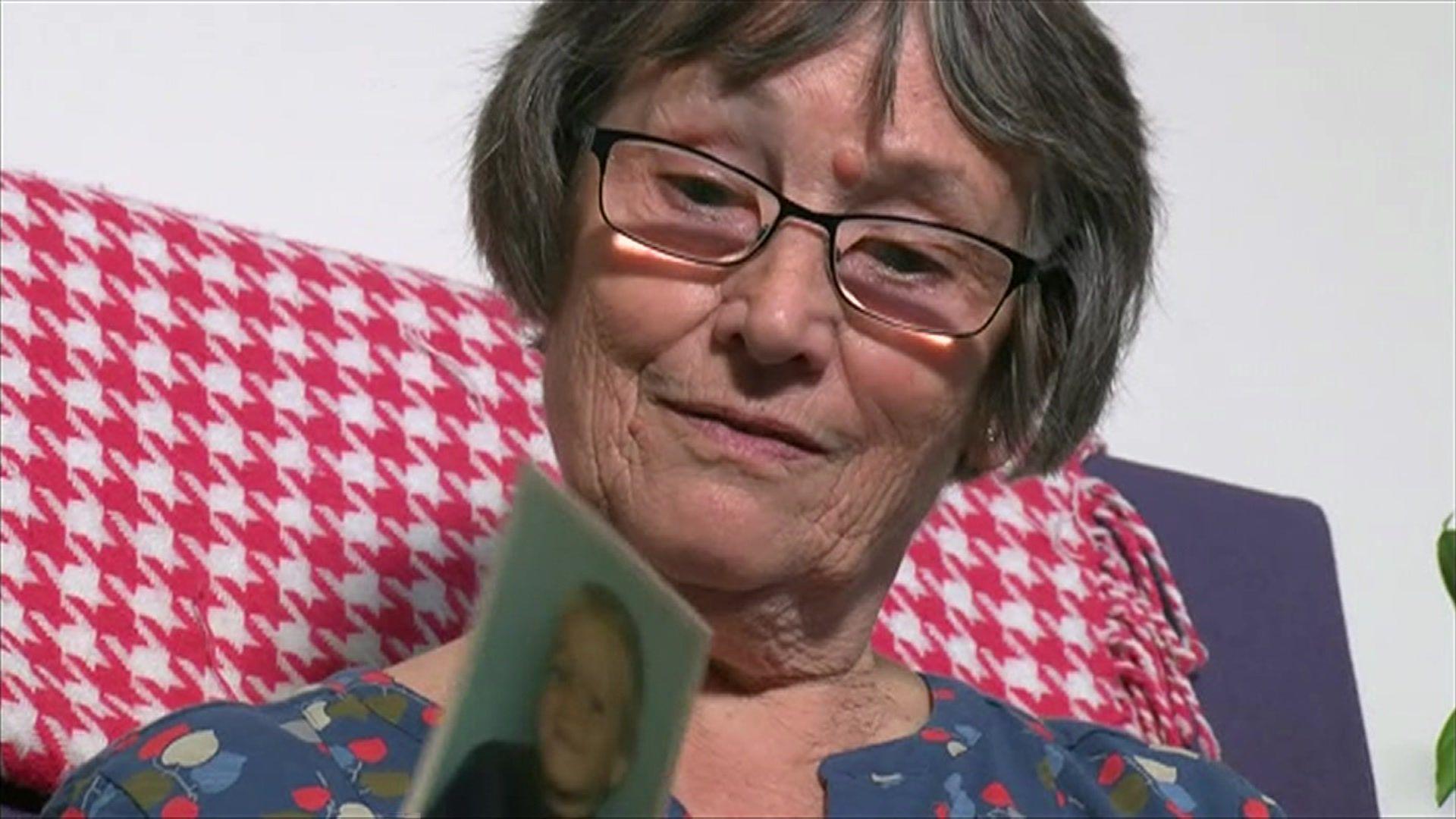 Margaret Parkes, who has short, greying hair, looks at a picture of Simon as a young boy