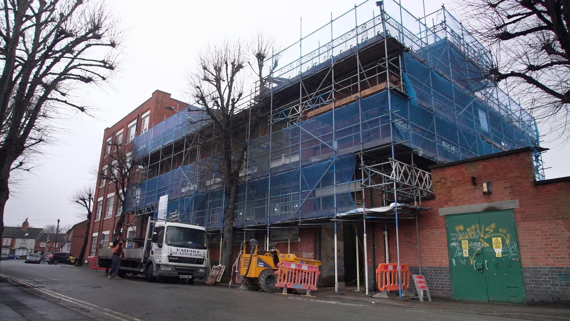 Outside of an old building in Loughborough covered in scaffolding.