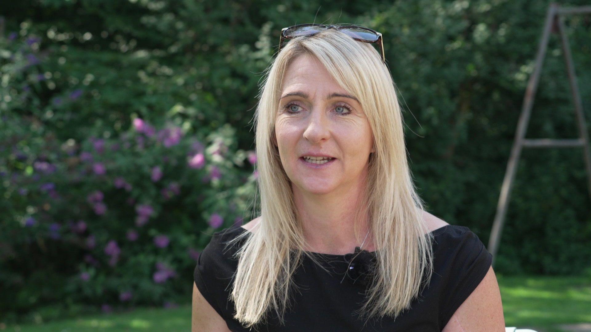 Cara Shardlow has long blonde hair and is wearing a black sleeveless top.