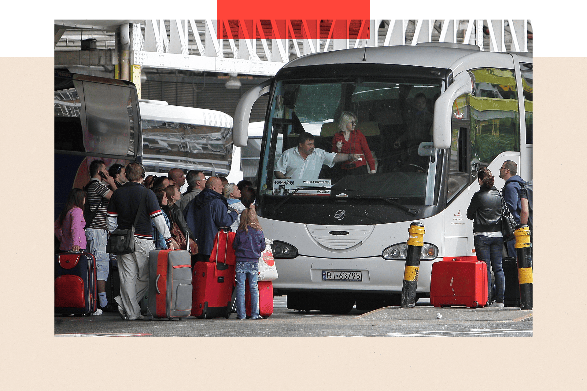 A bunch of people queue up to get on a white coach. Most of the people have red suitcases.