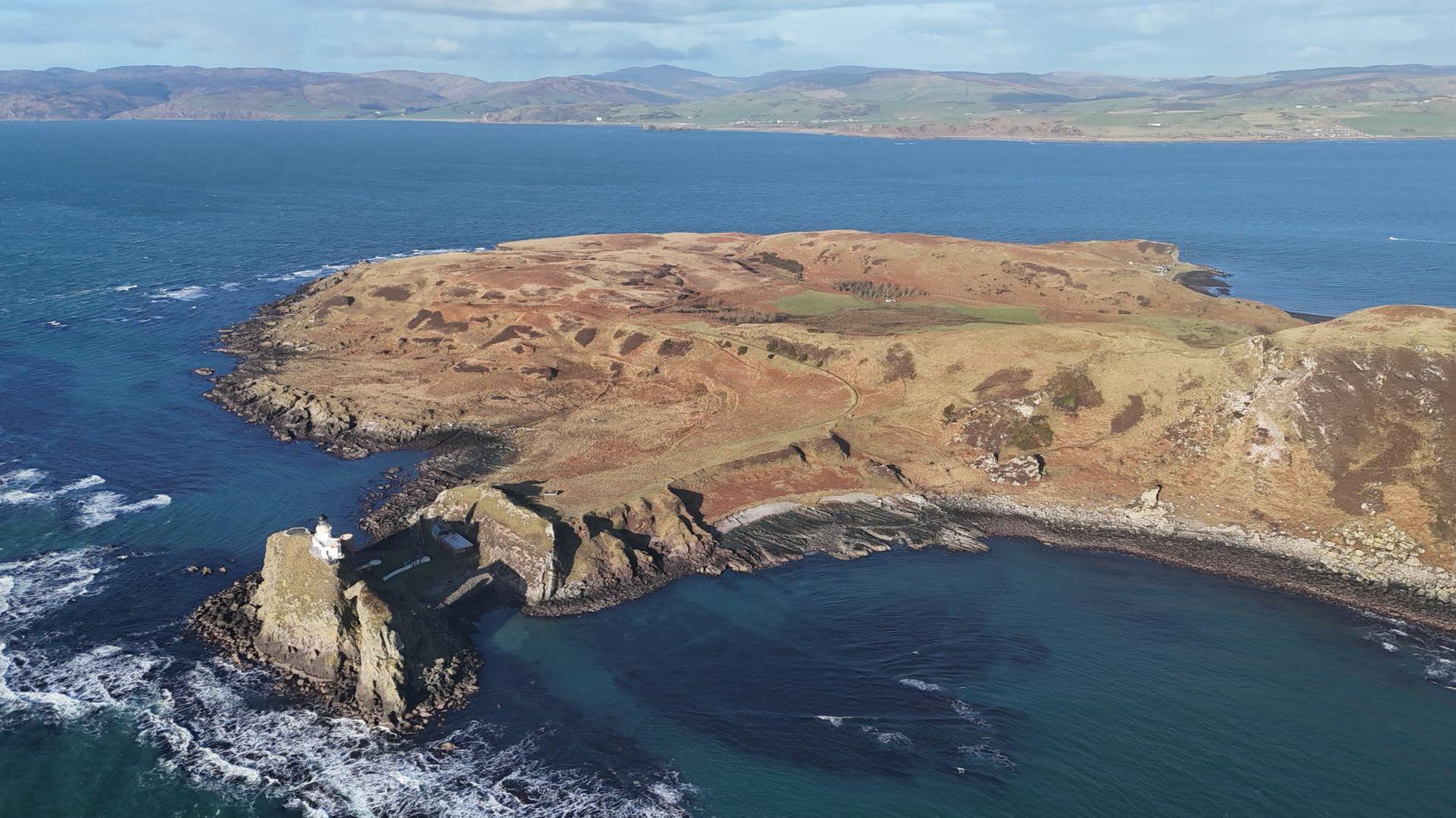 An aerial view of the island of Sanda and its lighthouse. The Kintyre peninsula is across the sea from it.