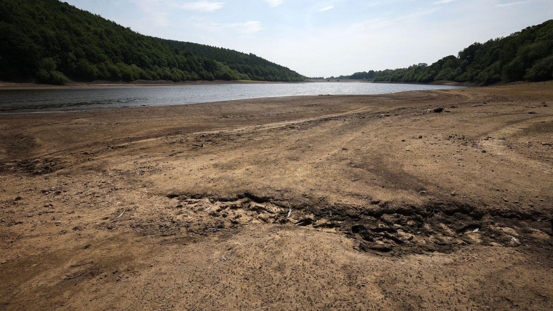 A dried expanse of land with some water in the distance.