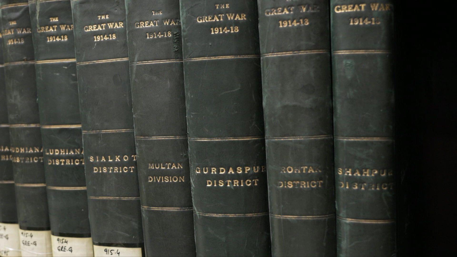Seven leather bound books in a line, with the names of different districts on them, all with the title 'The Great War 1914-1918' on them.