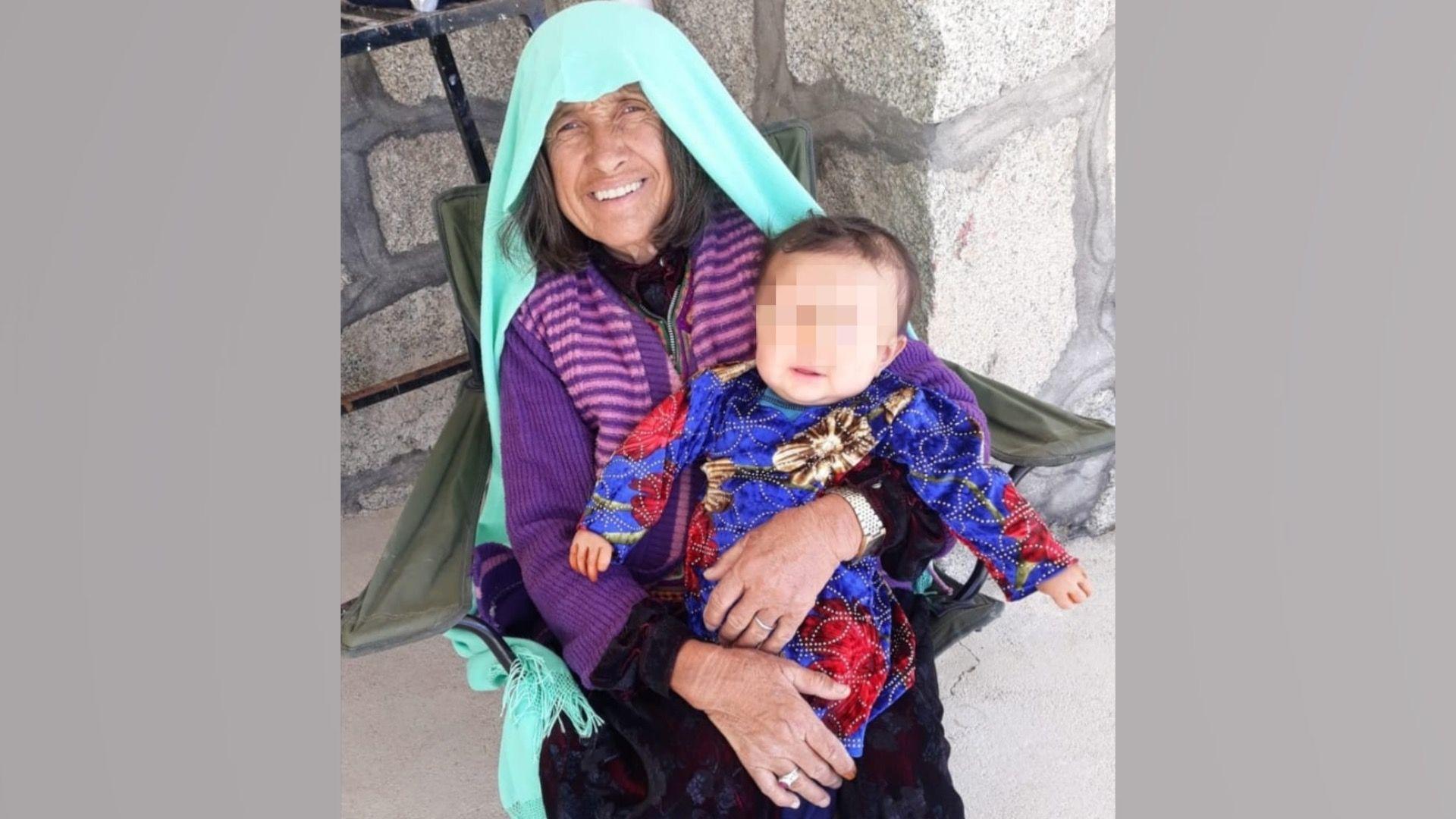 Pervin's grandmother is wearing a green headscarf and carrying a baby