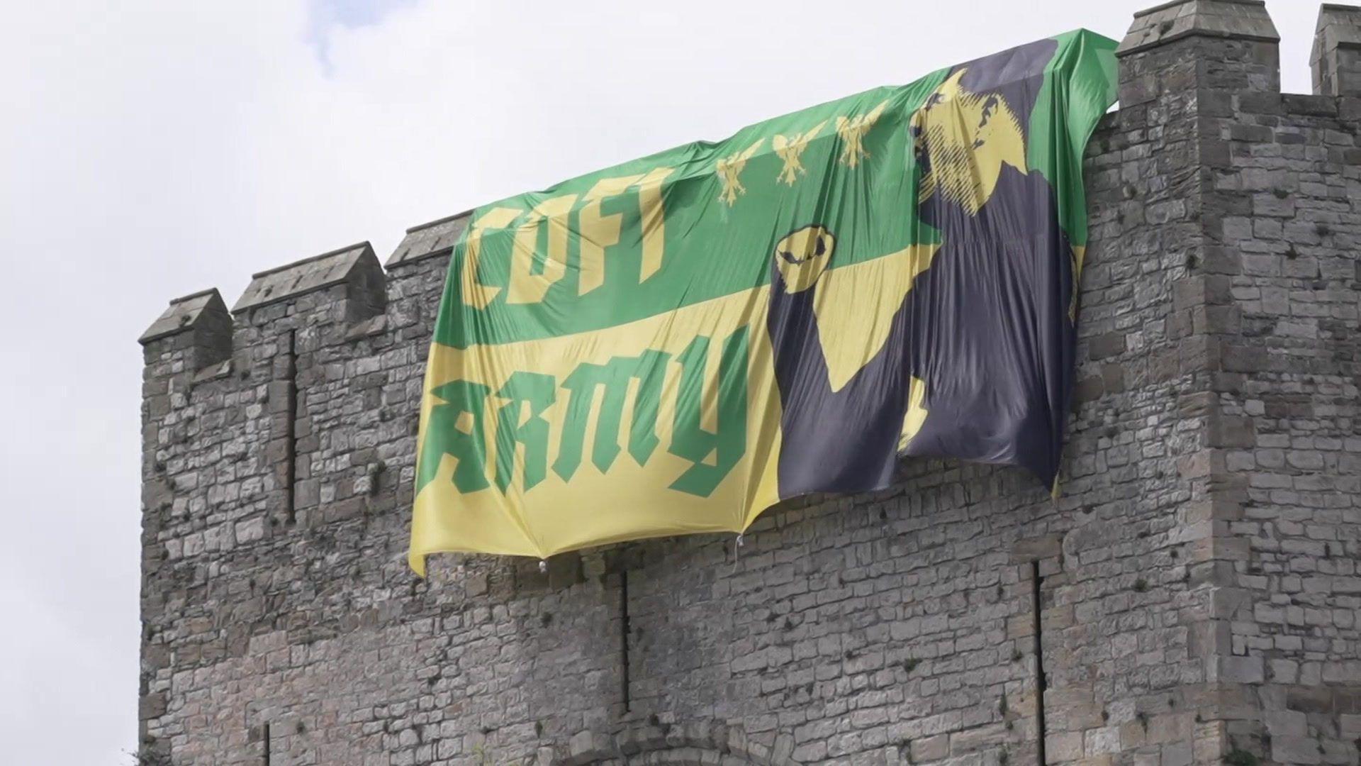Baner Cofi Army ar furiau Castell Caernarfon gyda llun o'r rheolwr Richard Davies