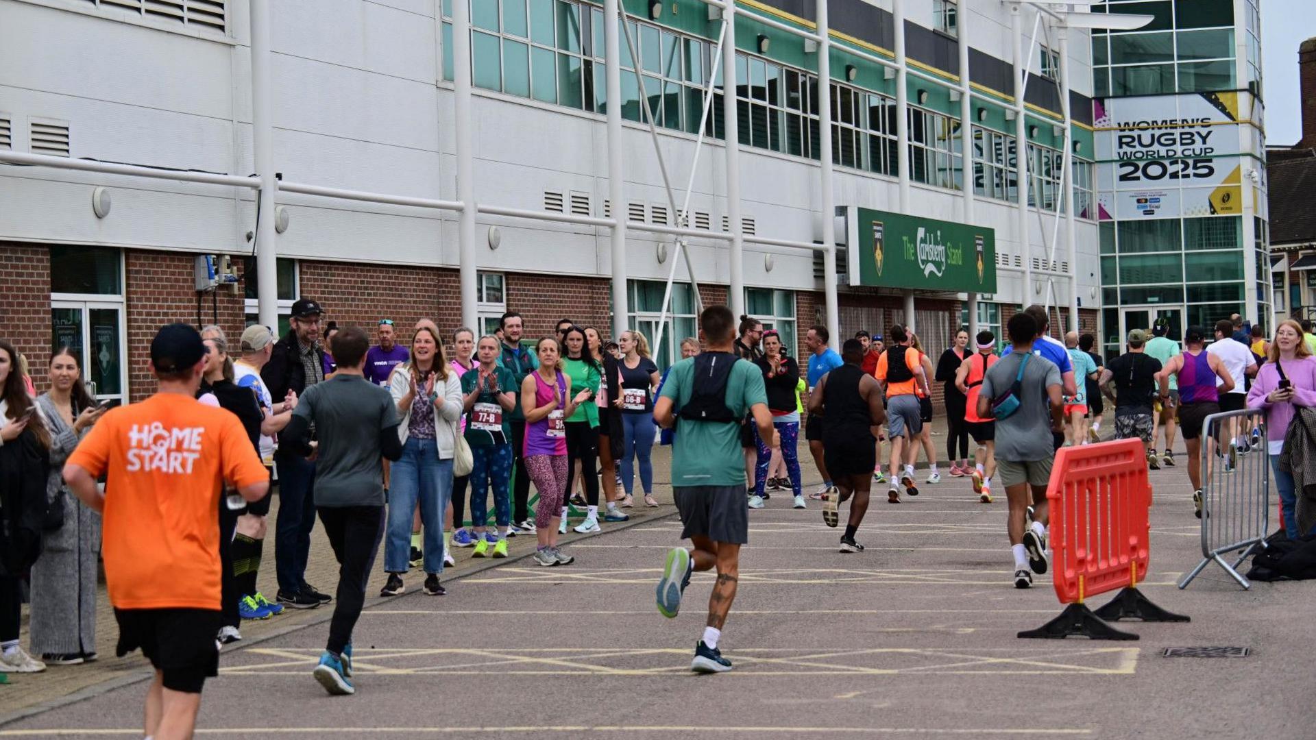 Crowds cheer runners as they pass the main stand at Franklin's Gardens stadium.