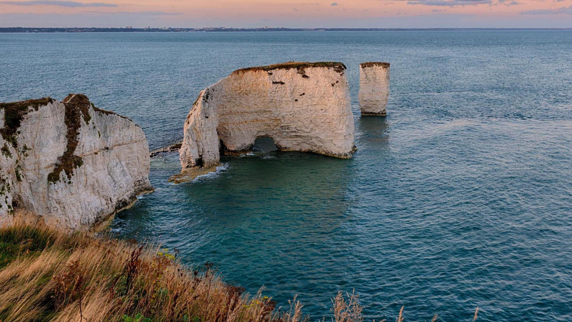 A view of Old Harry Rocks from a cliff edge. Its large rock formations have eroded over time, forming picturesque gaps in between. 