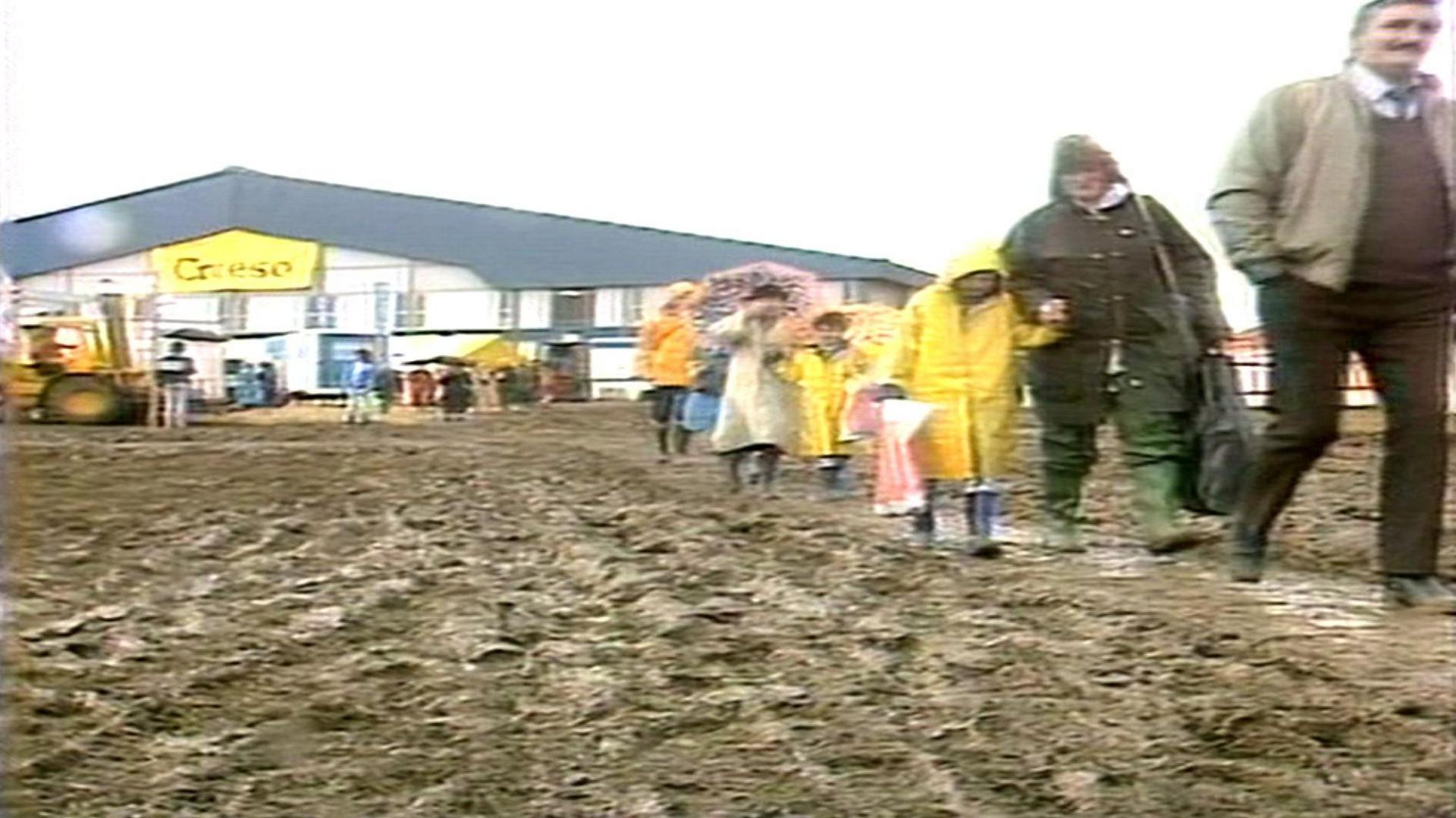 Pobl yn cerdded drwy'r mwd ar gae yr eisteddfod