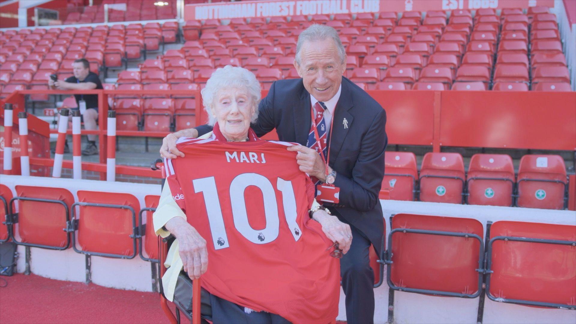 An older lady with a red football shirt saying Marj 101 on the back