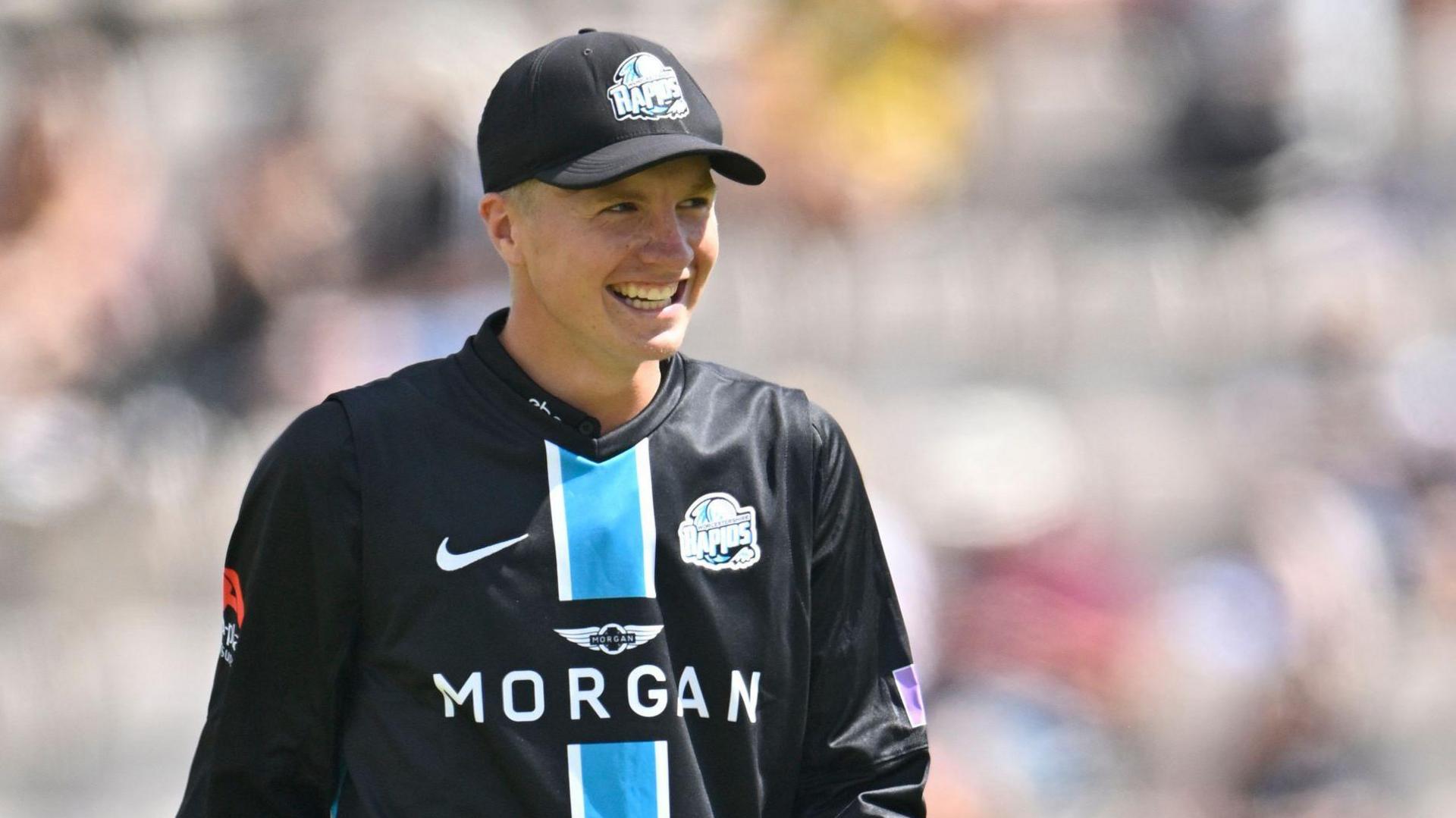 Henry Cullen in his black Worcestershire Rapids kit smiles as his side takes a wicket during a 50-over game