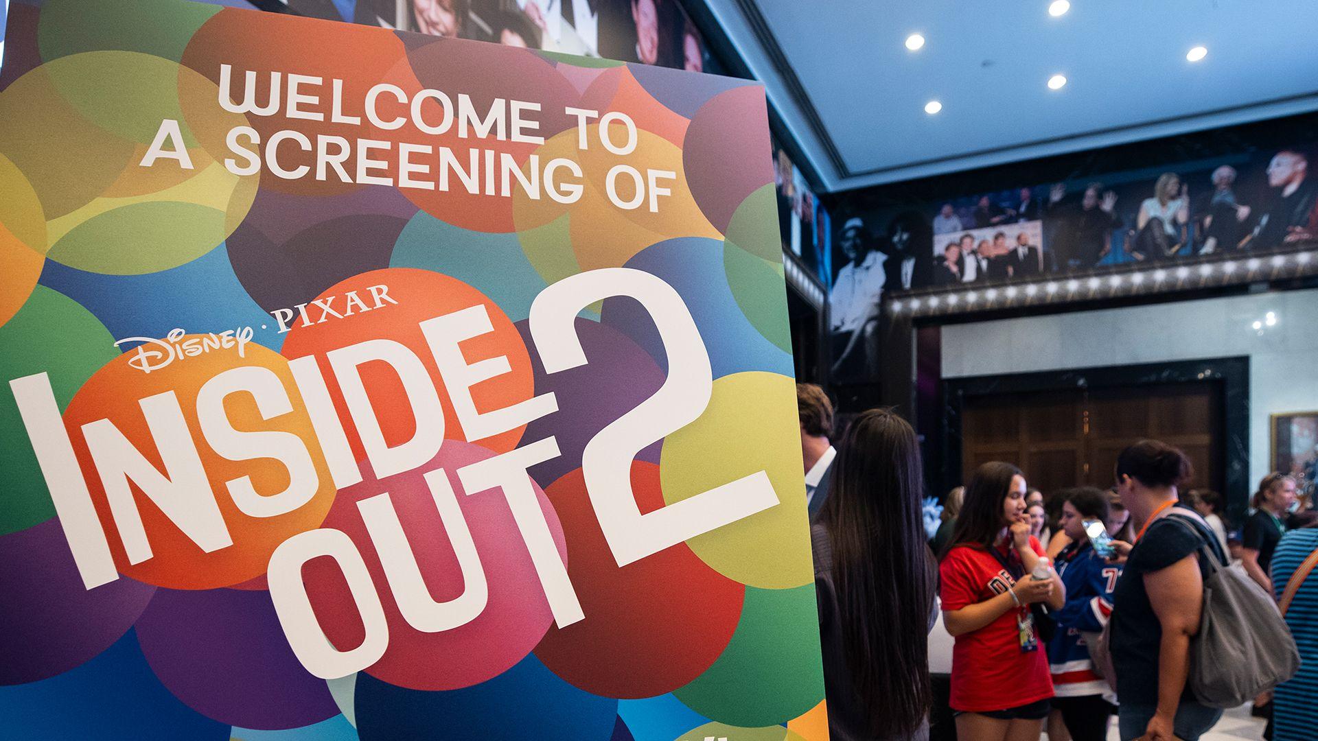 A poster saying "Welcome to a screening of Inside Out 2" with fans in the background