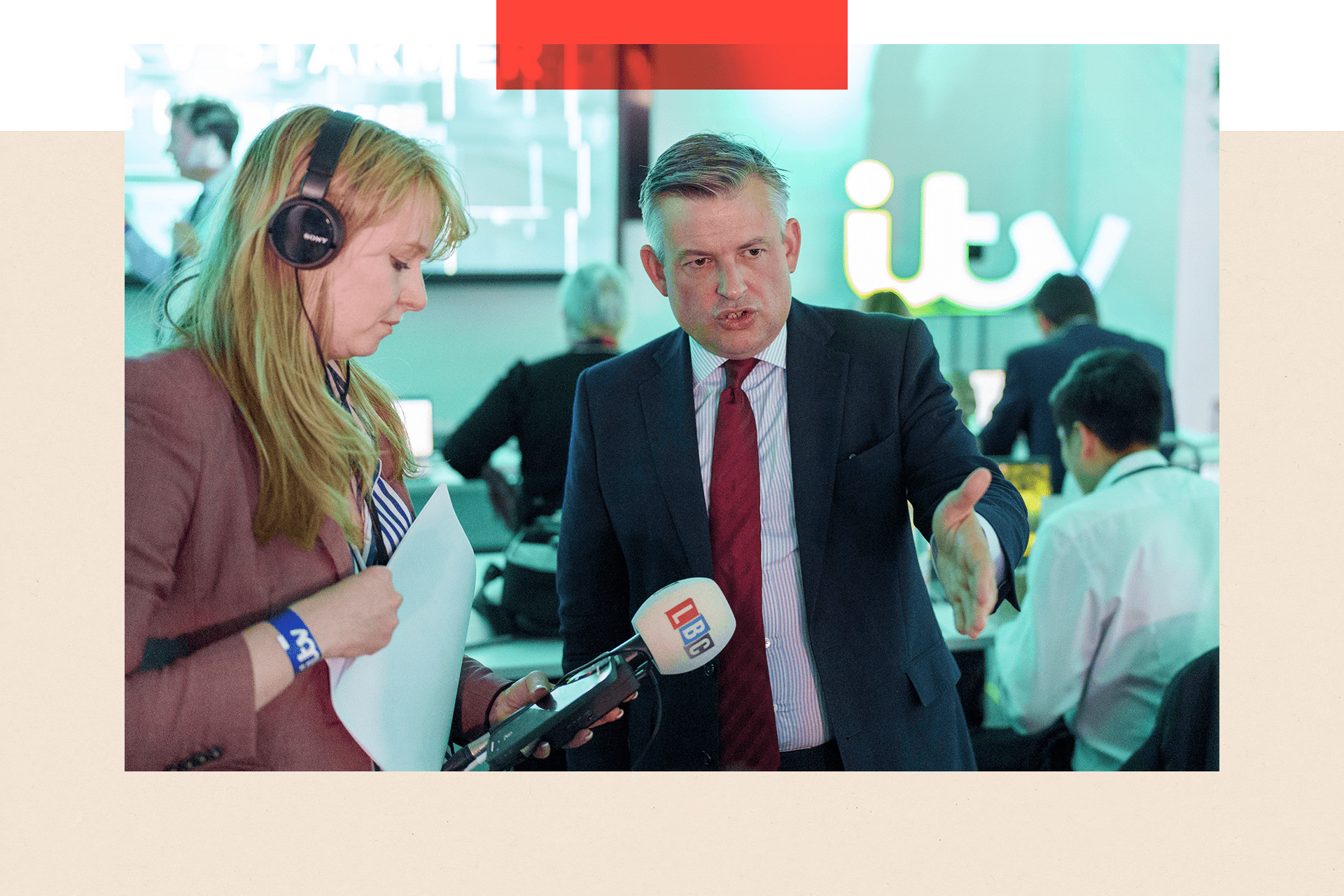 Jonathan Ashworth gives an interview to an LBC radio reporter. His left arm is outstretched and he is wearing a suit