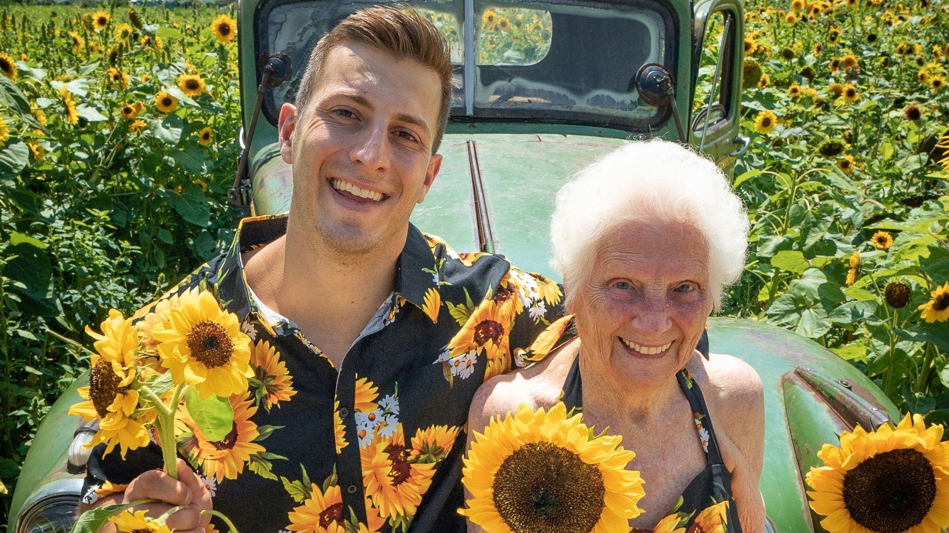 Young man and old woman hold sunflowers