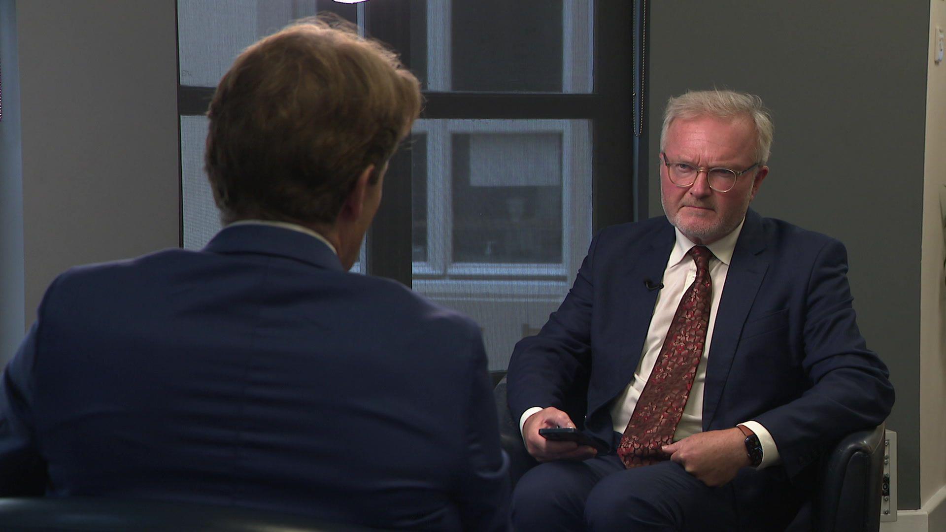 BBC South's political editor Peter Henley during his interview with Reform UK's Richard Tice. They are sitting in a room. Mr Henley is looking at Mr Tice. He is holding a smart phone. Mr Tice has his back to the camera.
