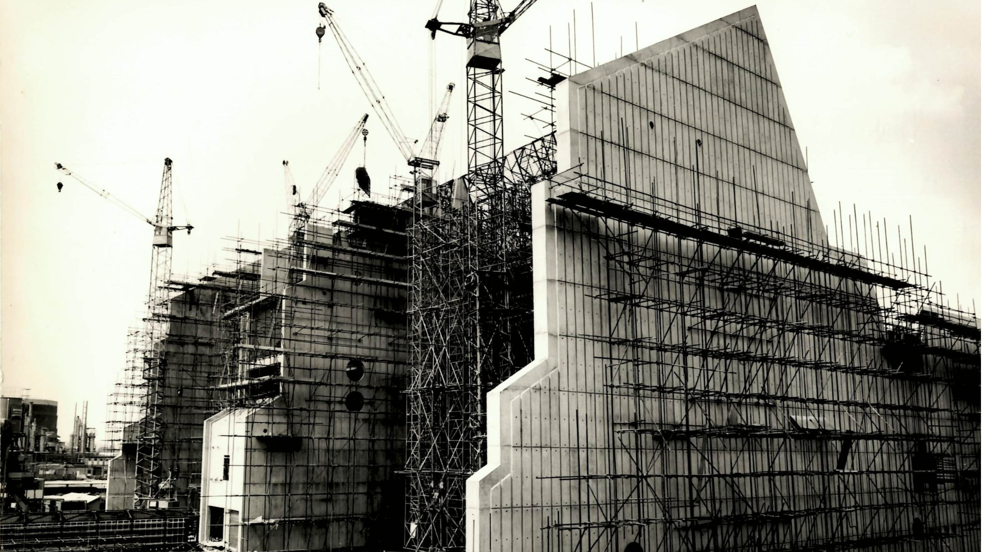 Tall concrete factory building under construction with scaffolding 